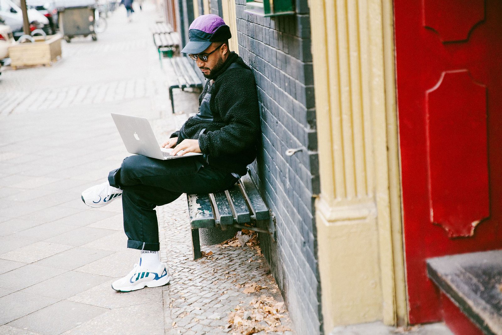 DJ Nico Adomako working on a laptop on a Berlin street bench