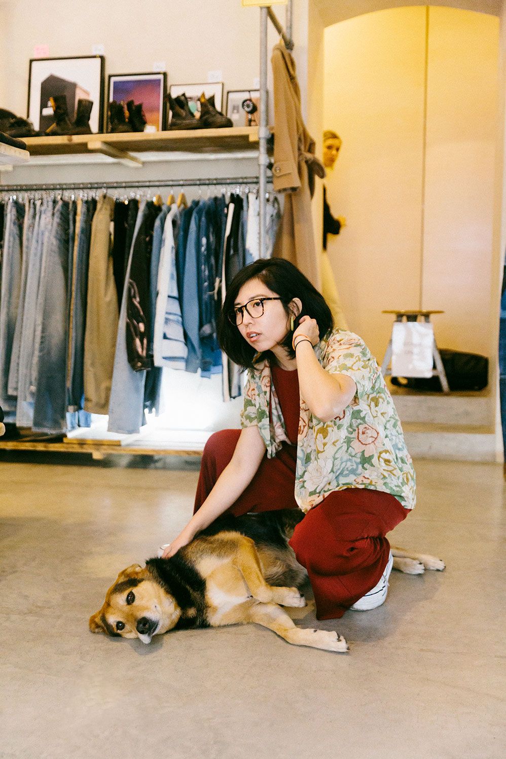 Ruohan Wang crouching with a dog in a vintage clothing shop
