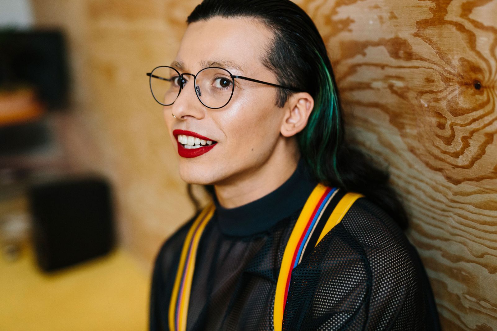 Musician Mikey Woodbridge in round Ace & Tate frames against a plywood wall, Berlin
