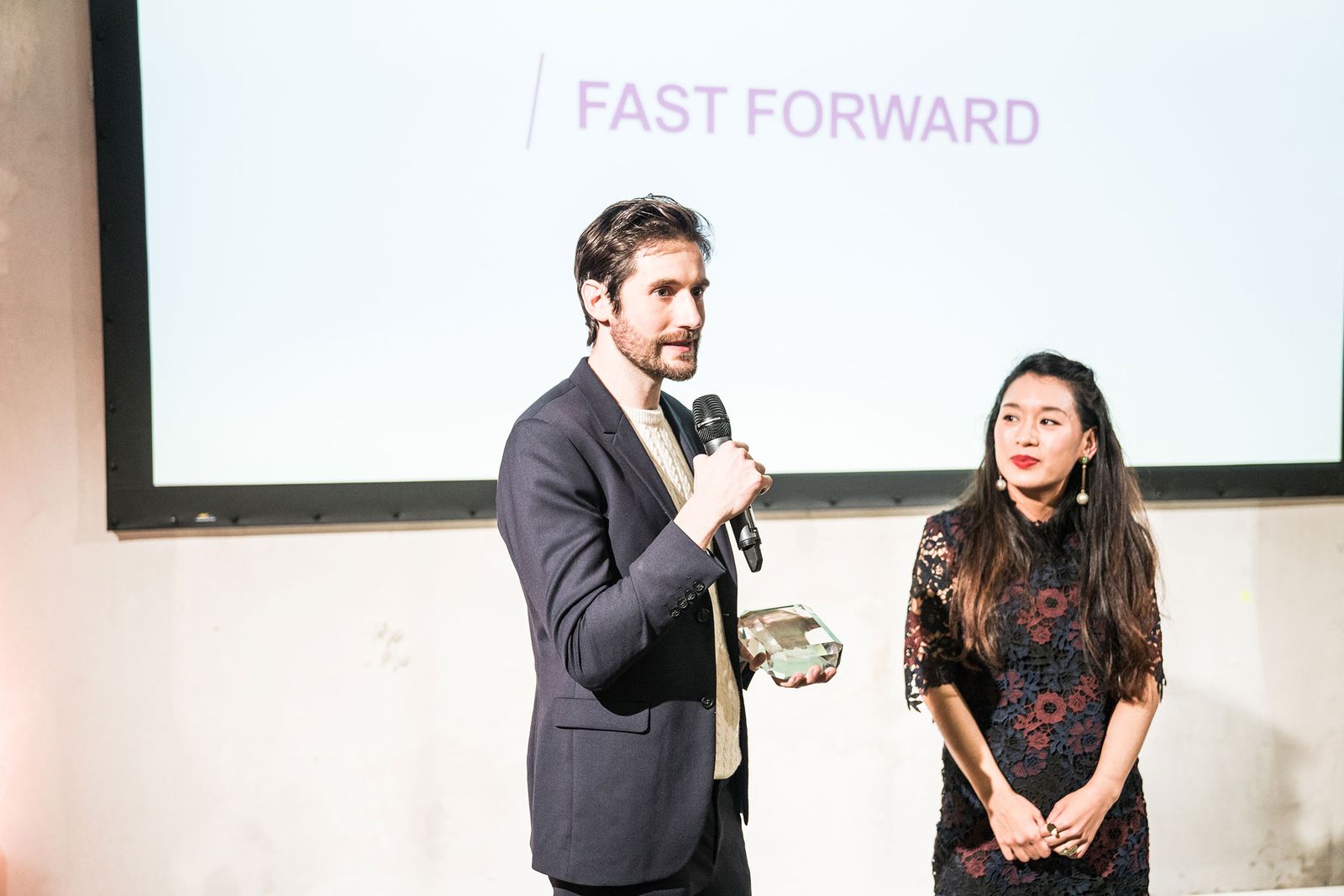 Award winners speaking on stage in front of a projection at the AD Design Award