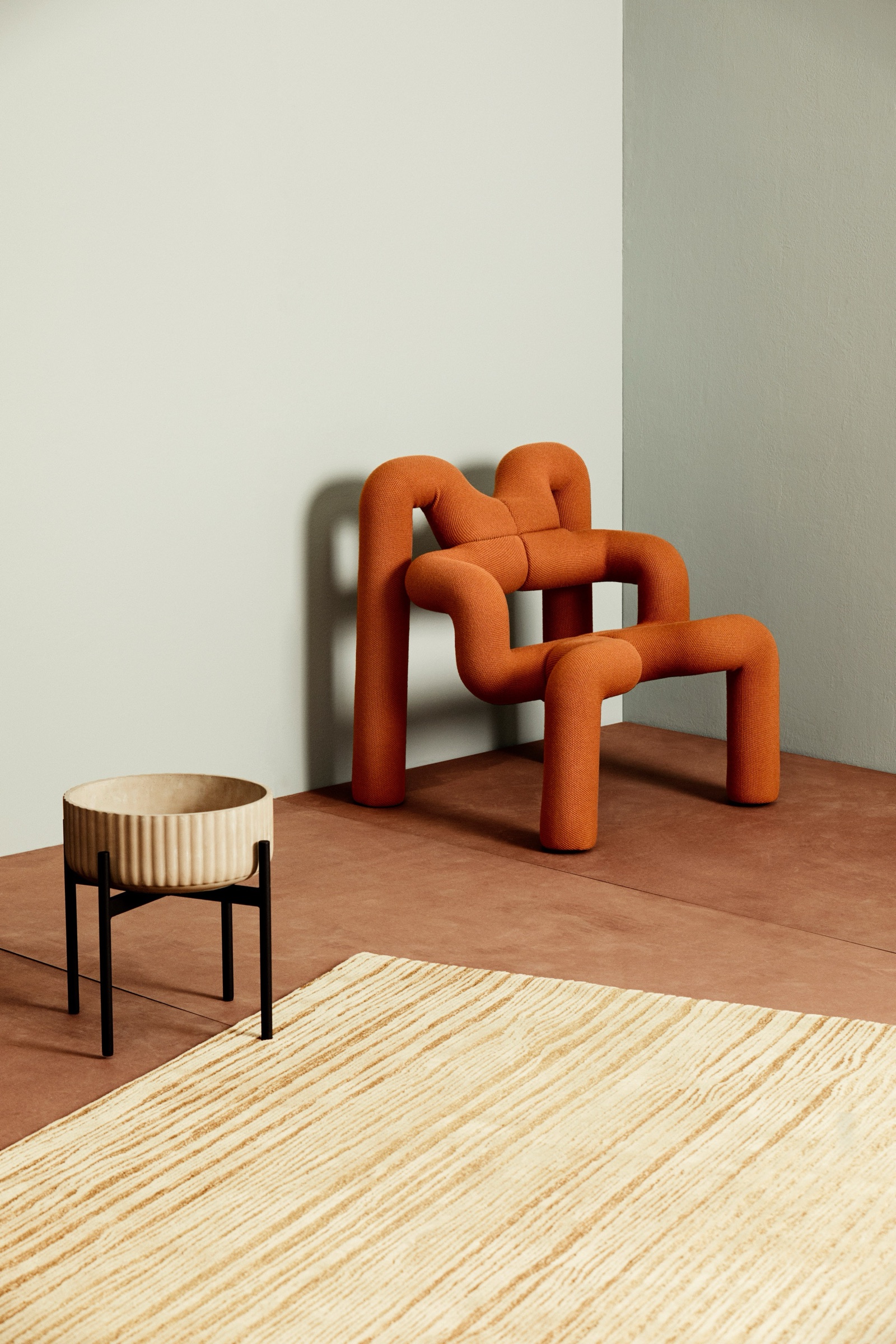 Orange sculptural armchair and side table in a pale green room, AD Magazin editorial image