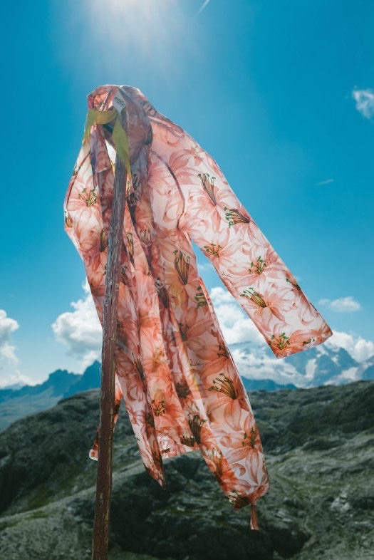 Floral scarf on a pole against a blue mountain sky, adidas Journeys lookbook