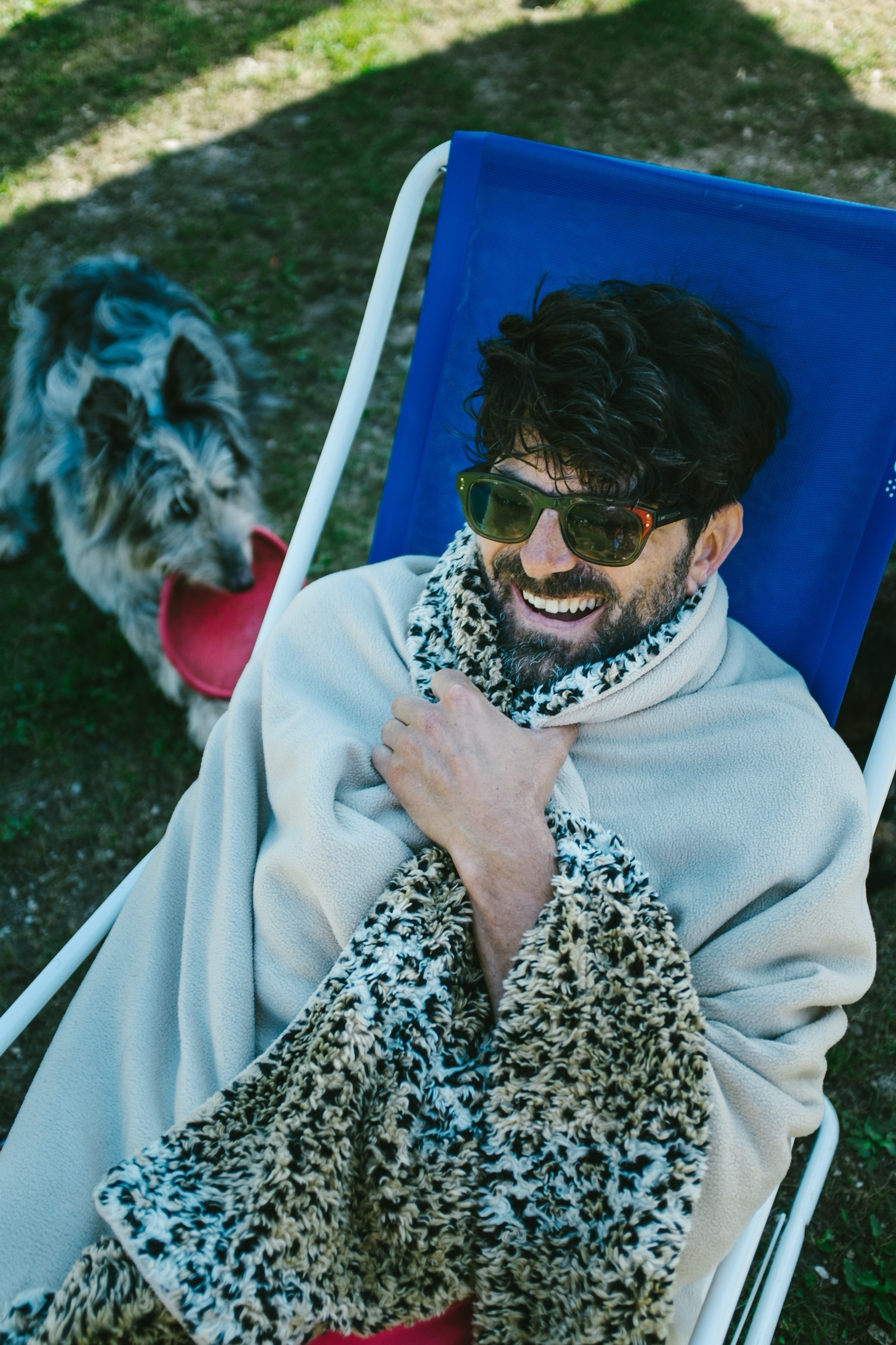 adidas Journeys rider wrapped in a blanket on a deckchair, with a dog behind