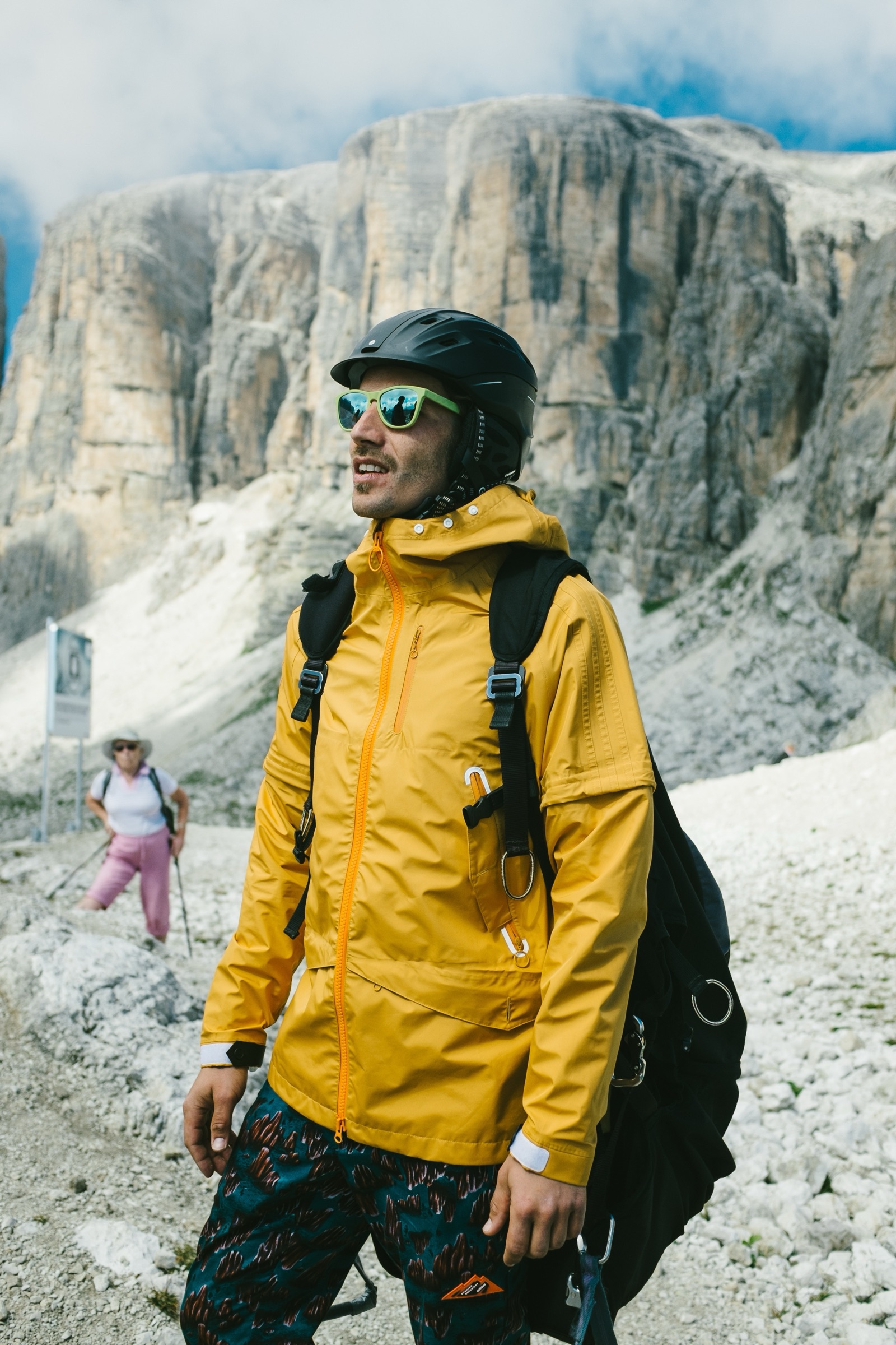 adidas Journeys rider in a yellow jacket and helmet below Dolomites rock faces