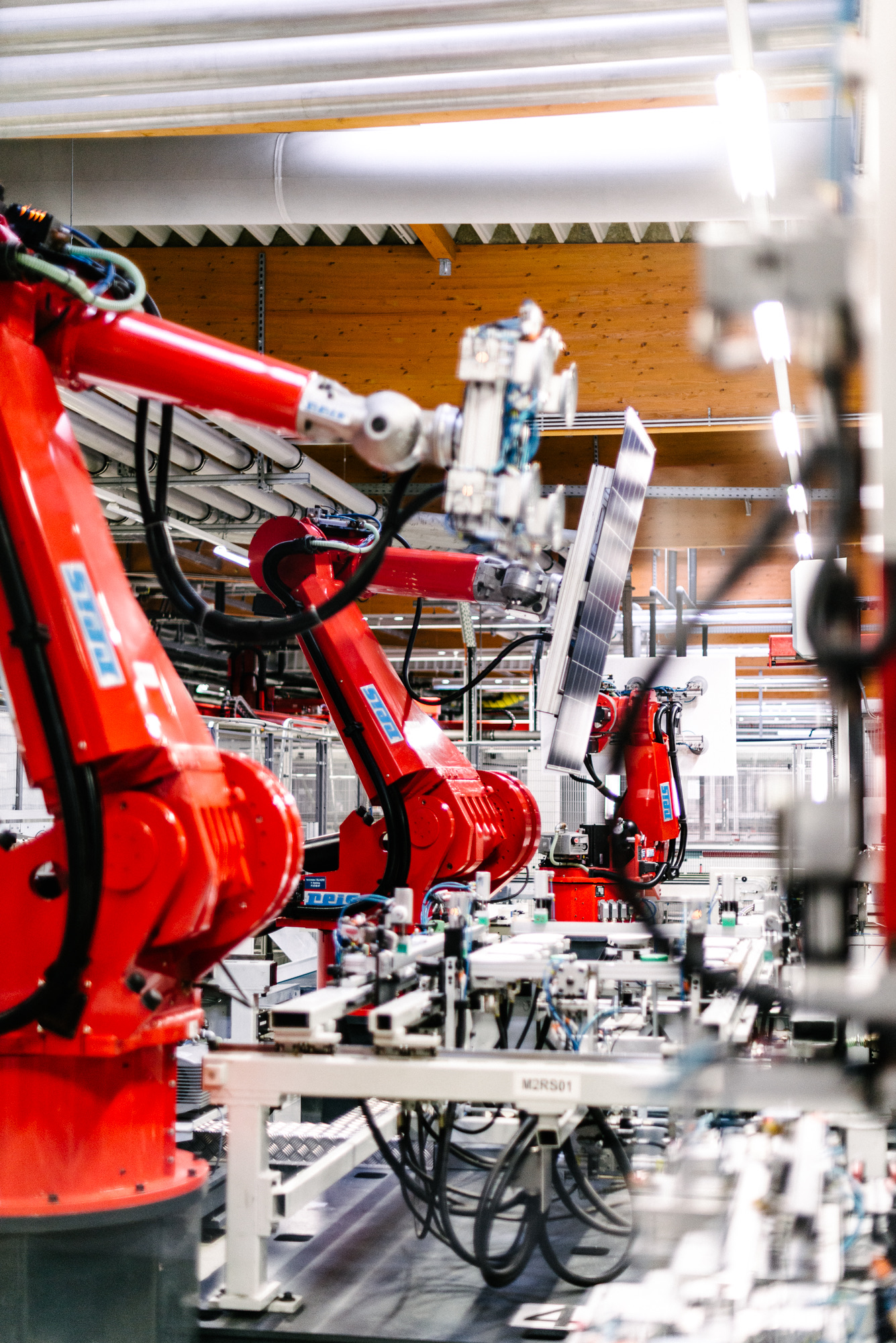 Red robot arms on the aleo solar panel production line