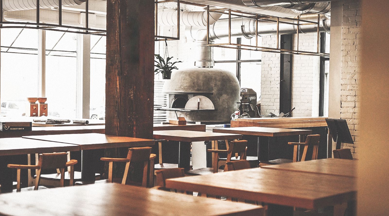 Brutø dining room with wooden tables and the wood-fired oven