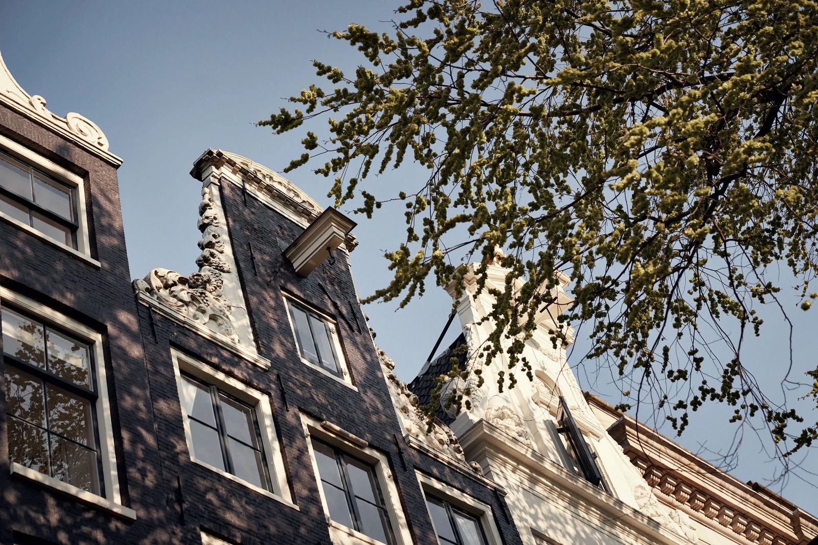 Amsterdam canal house gables against a blue sky, ClassPass #bethebalance editorial