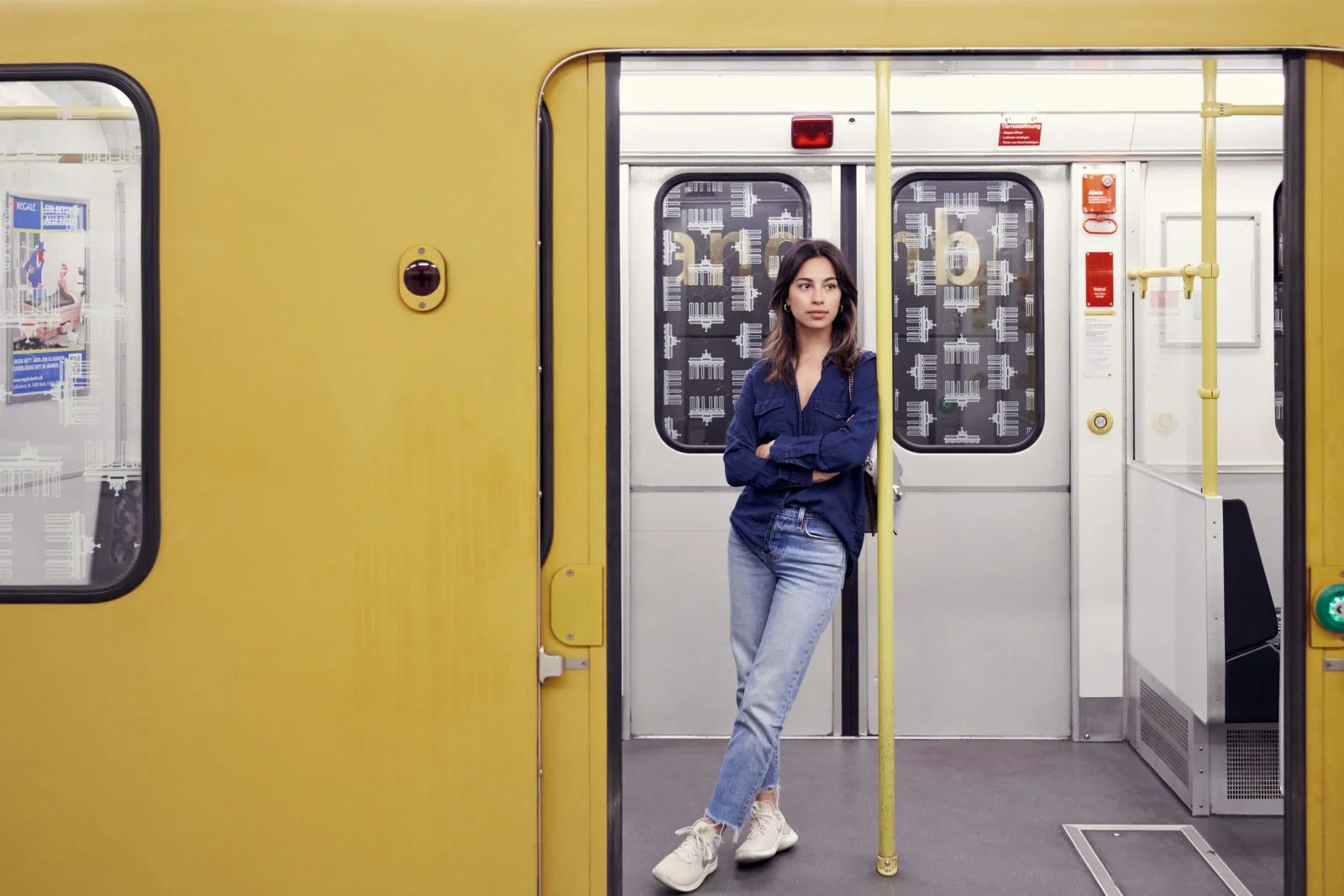 Woman leaning in the doorway of a yellow Berlin U-Bahn carriage, ClassPass #bethebalance editorial in Berlin