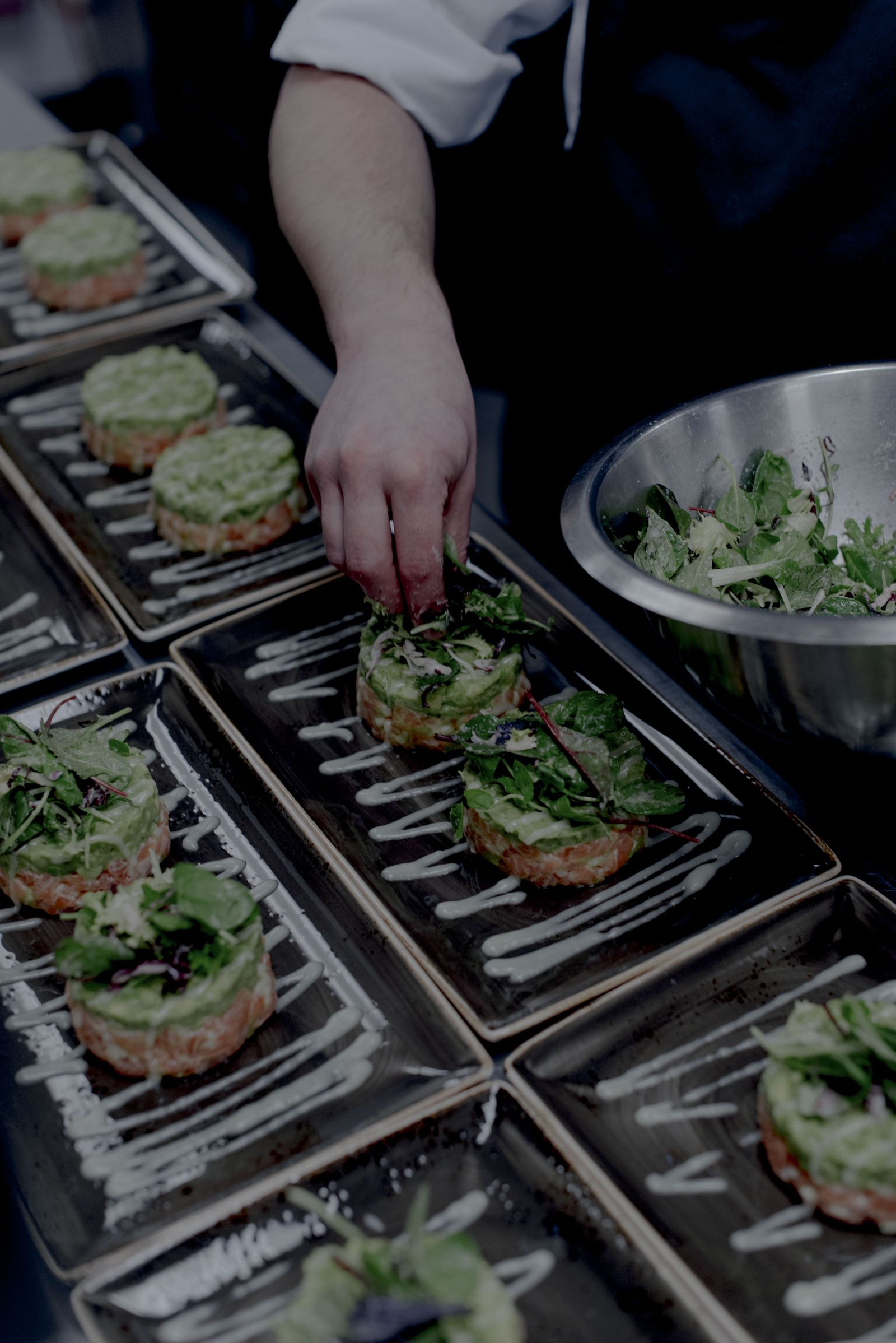 Chef plating rows of starters on steel trays for the CLOSED dinner