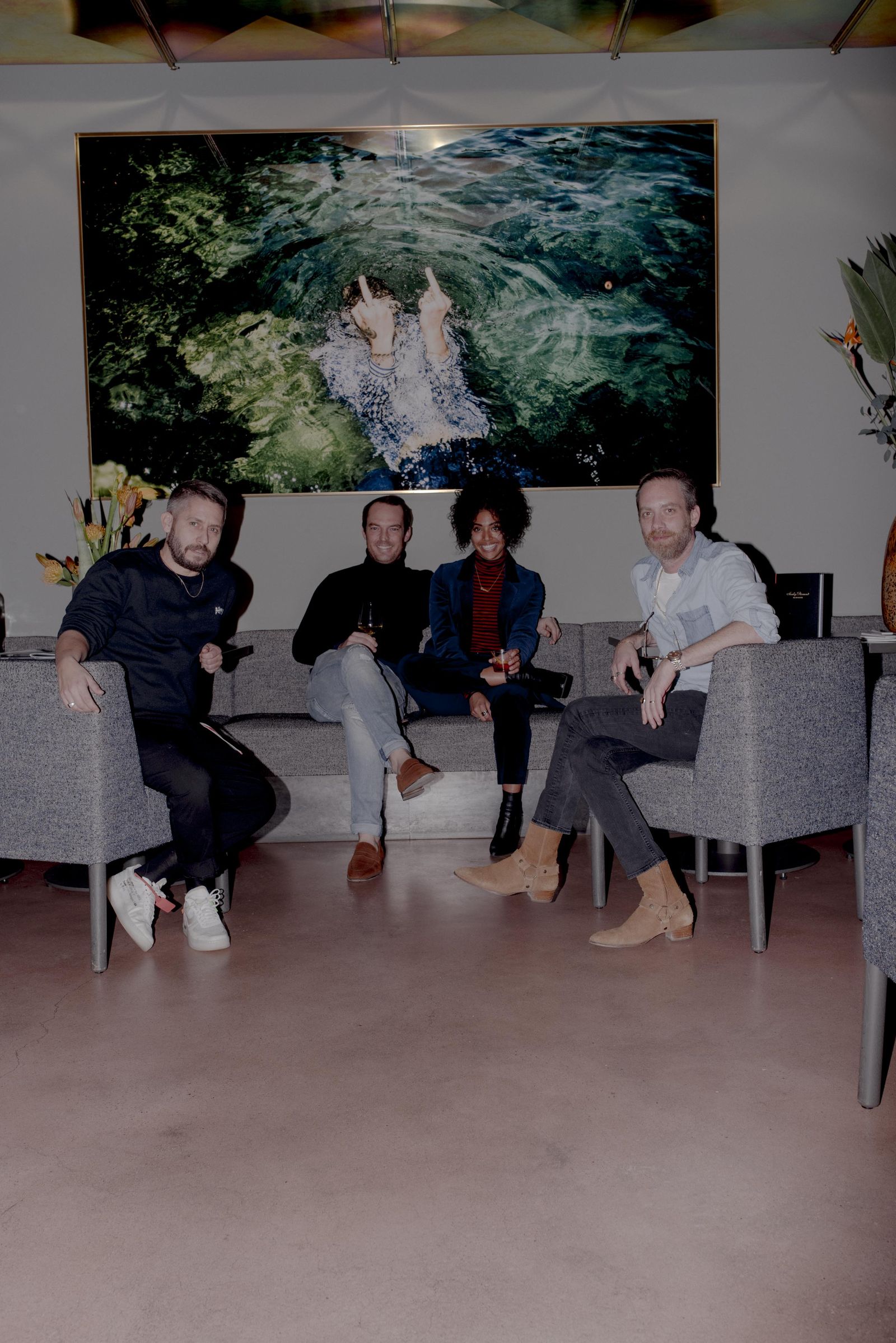 Four speakers on a grey sofa under a large painting at the CLOSED talk, 2018