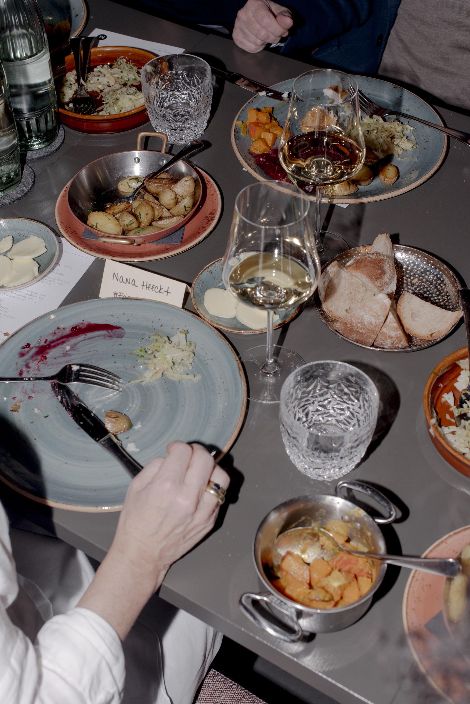 Shared plates, bread and wine glasses on the table at the CLOSED dinner