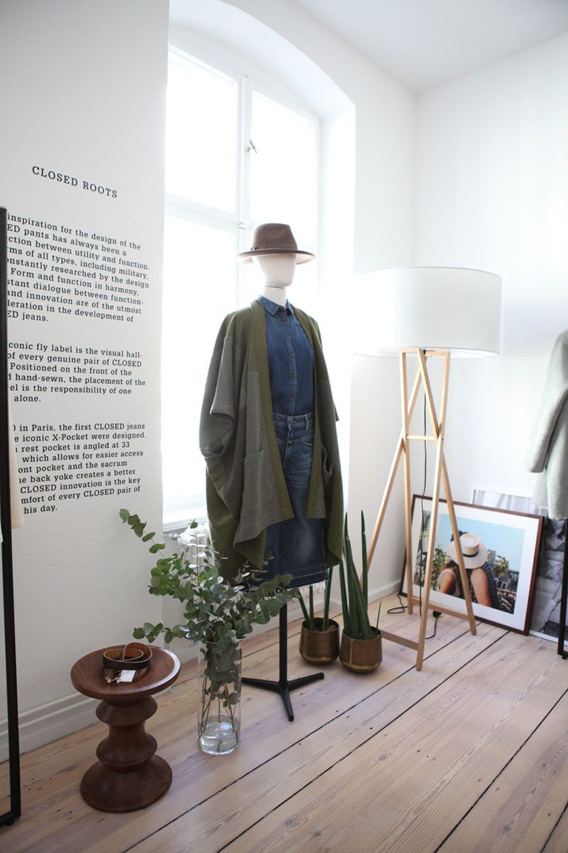 Mannequin in a hat and long green coat beside a wall text in the apartment, German Press Days