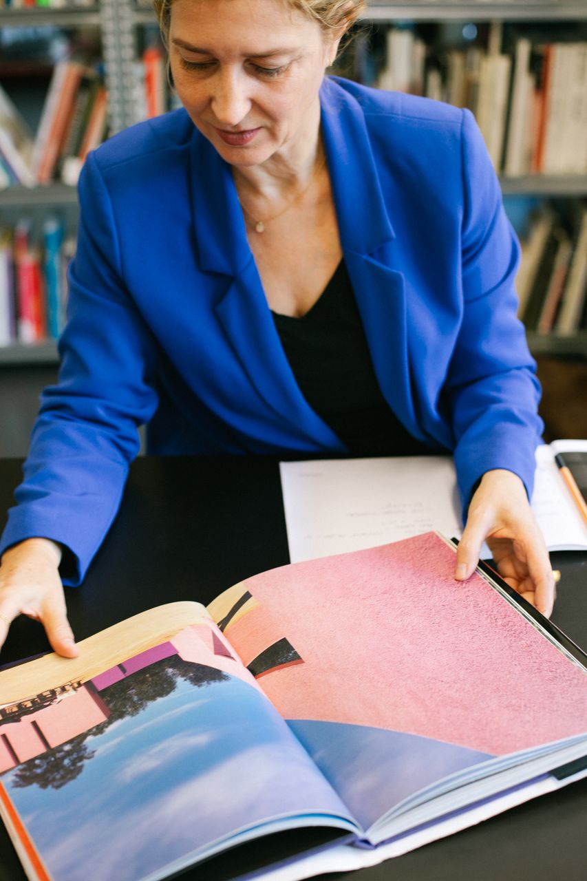 Architect leafing through a photo book at her desk, Berlin