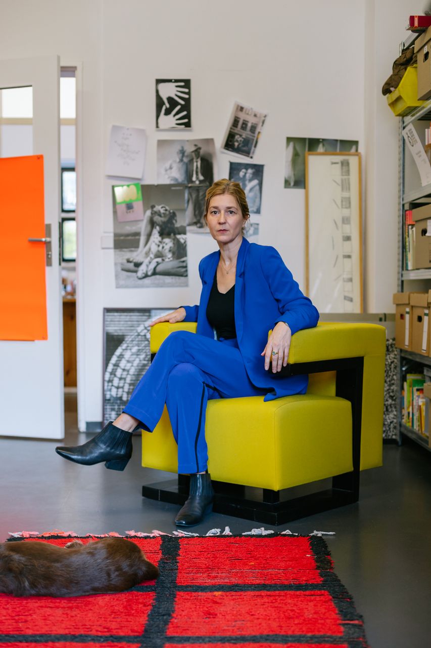 Architect in a blue suit sitting in a yellow armchair in her Berlin studio