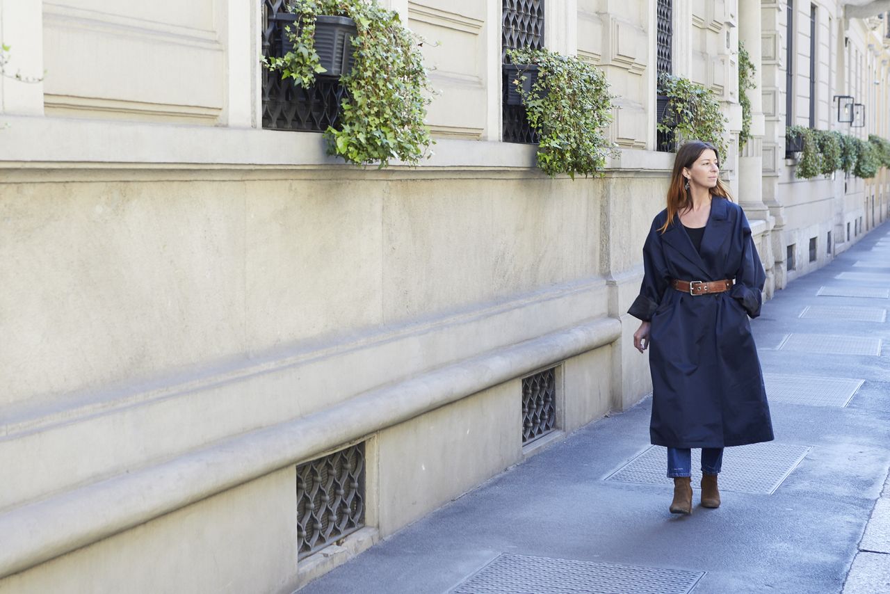 Ceramicist in a long navy coat walking along a Milan street