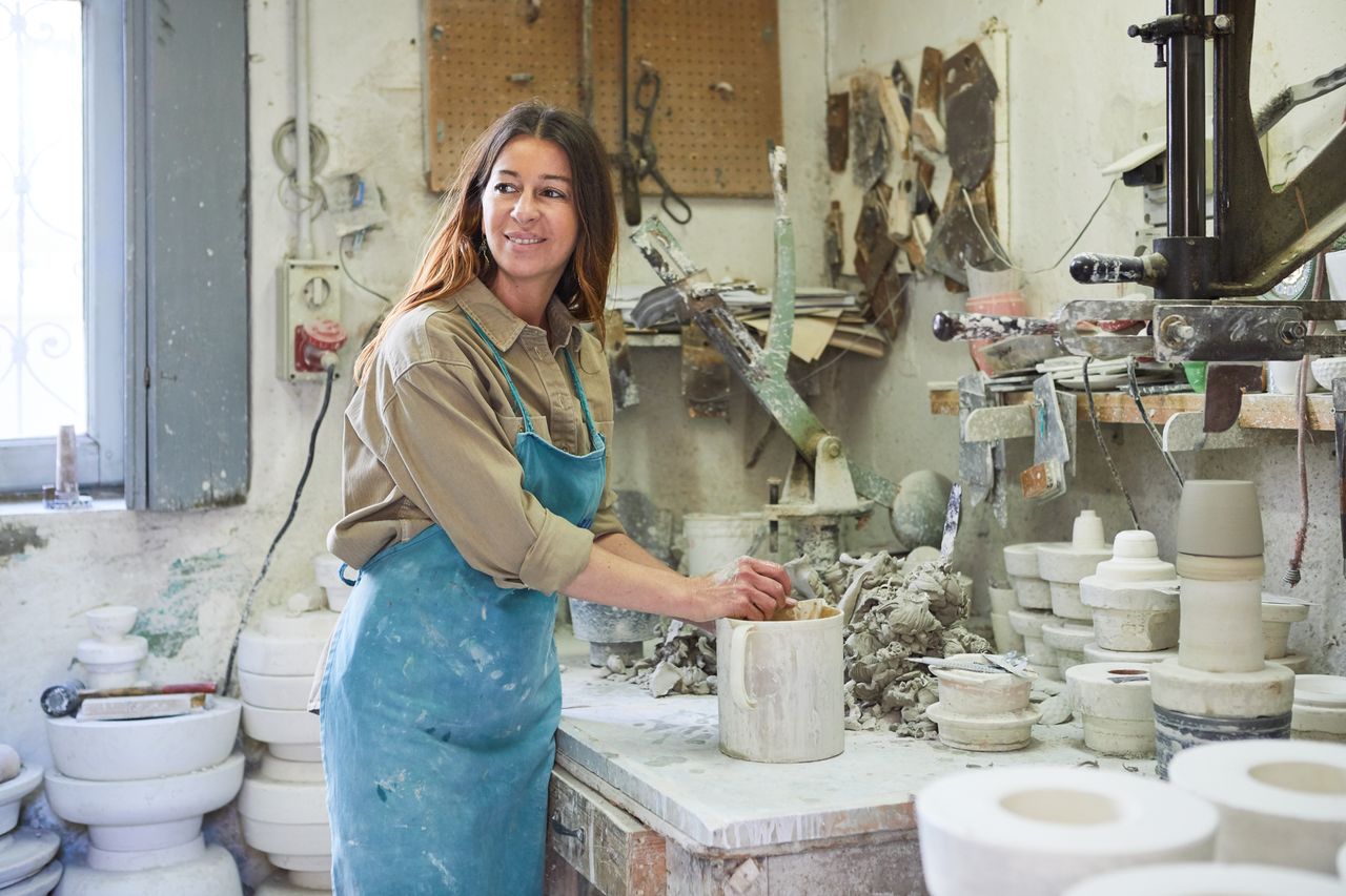 Ceramicist in an apron working with plaster moulds in a ceramics workshop near Milan