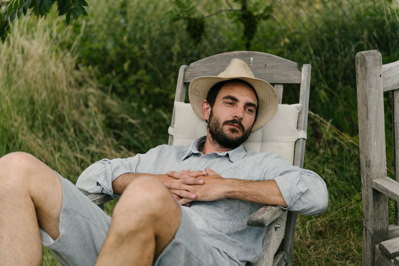 Photographer in a straw hat resting in a wooden garden chair, Uckermark
