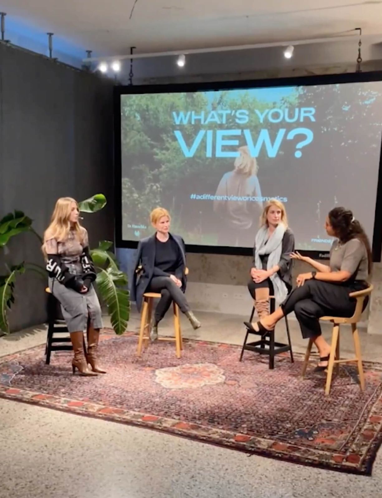 Four women on stools in a panel talk in front of a What's your view? projection, Friends Space