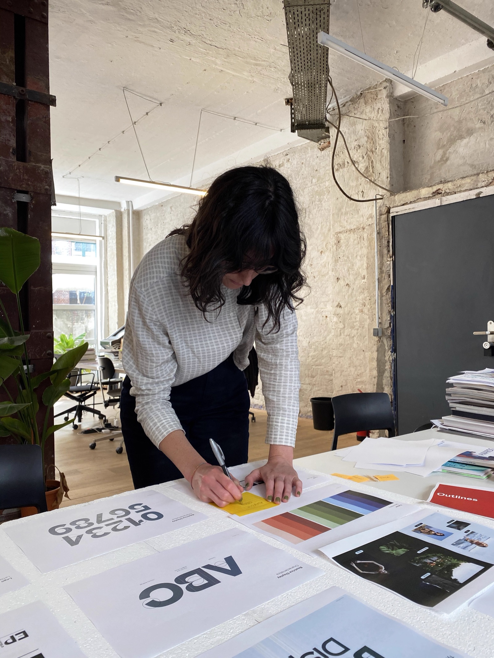 Designer reviewing printed Episode Hotels identity sheets in the studio