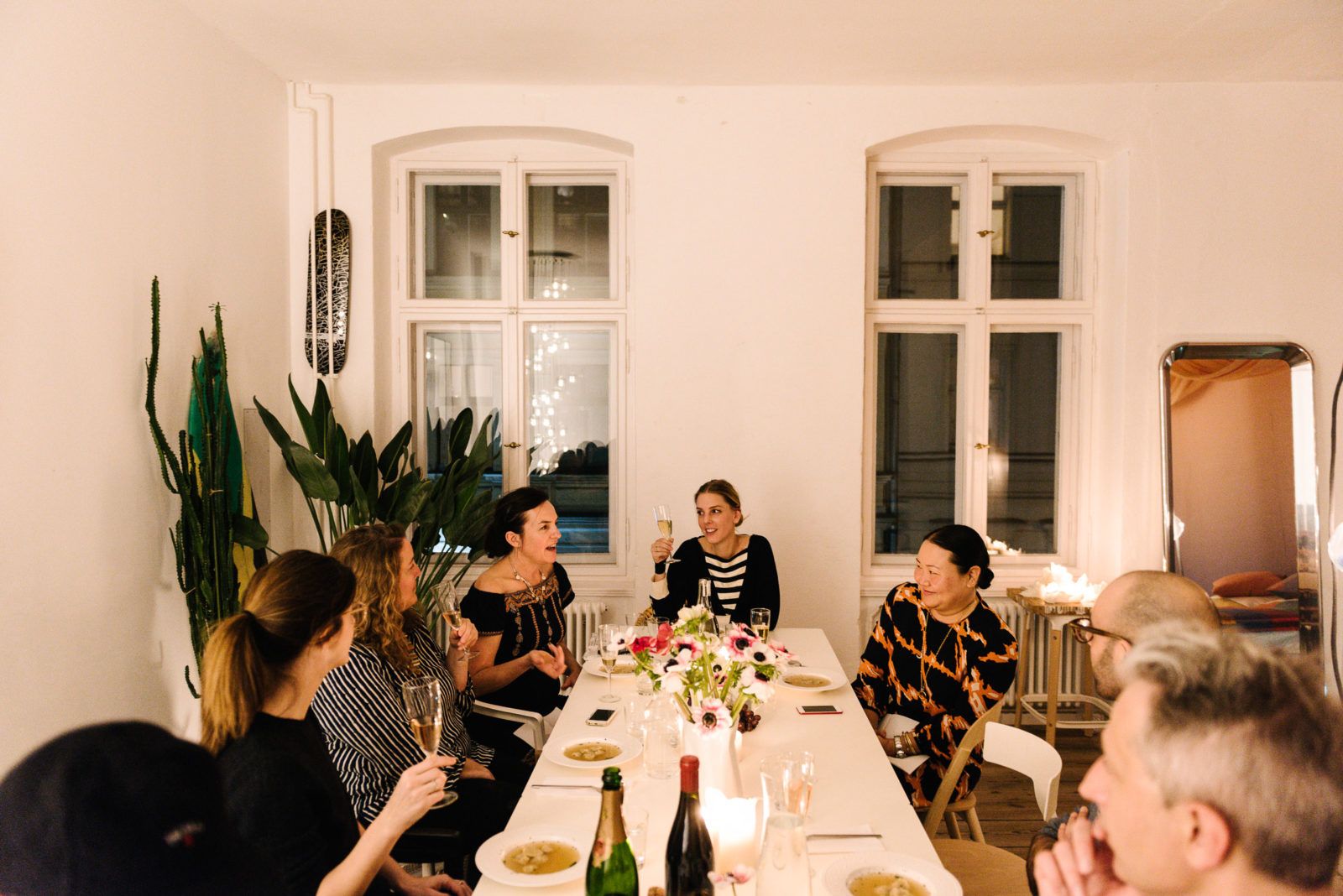 Guests in conversation around a dinner table in the Friends Apartment