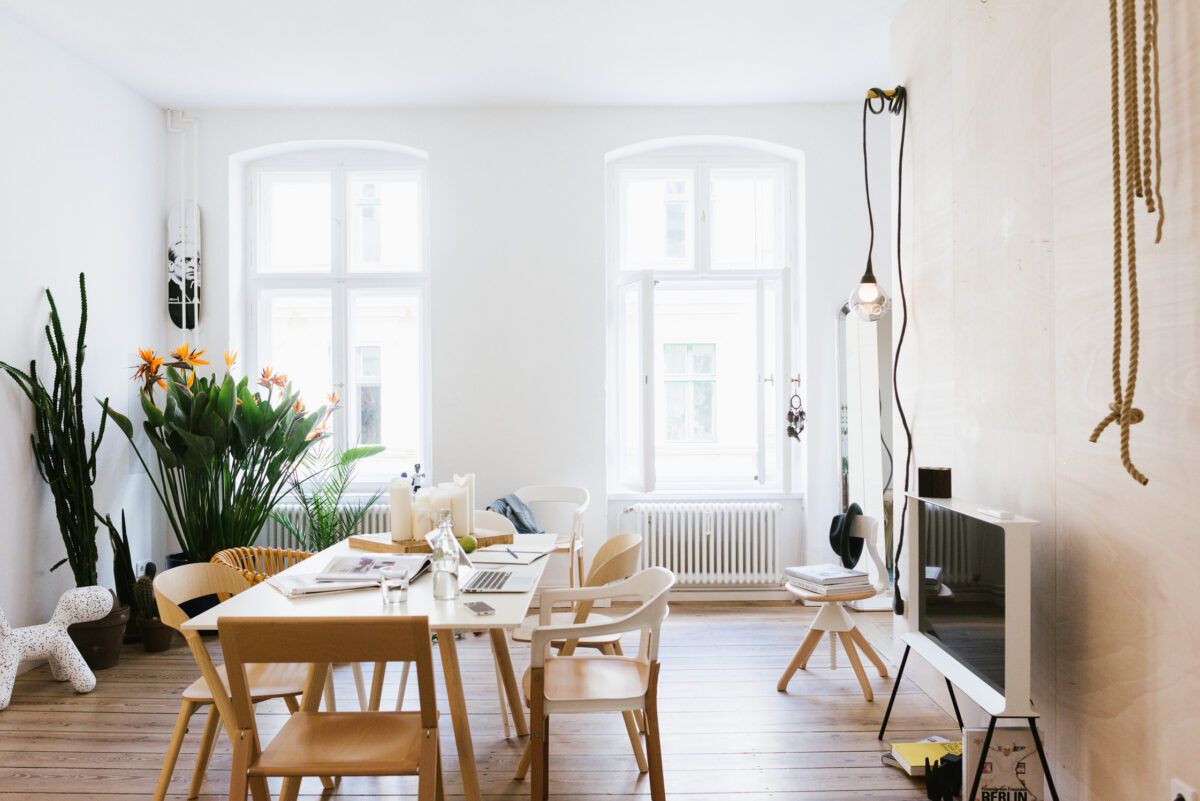 White dining room with wooden chairs and plants in the Friends Apartment, Berlin