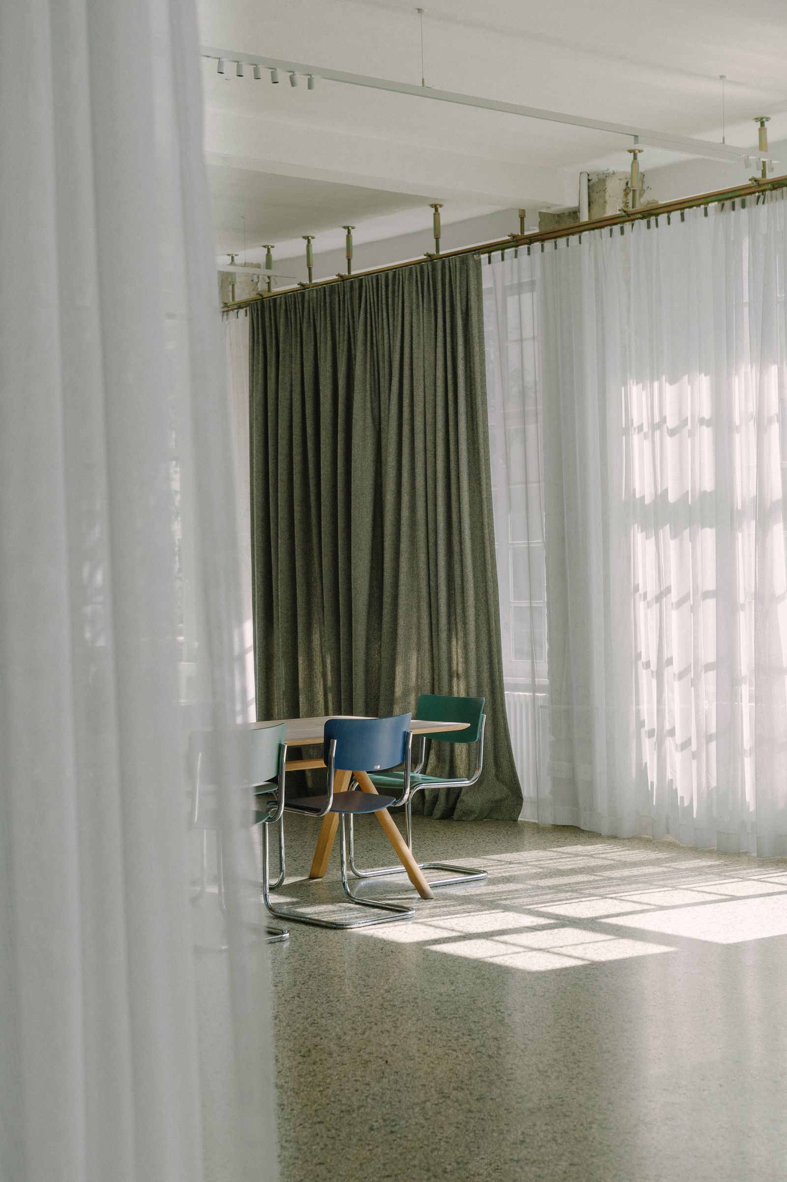 Sunlight through sheer white curtains on the terrazzo floor of the Friends Space