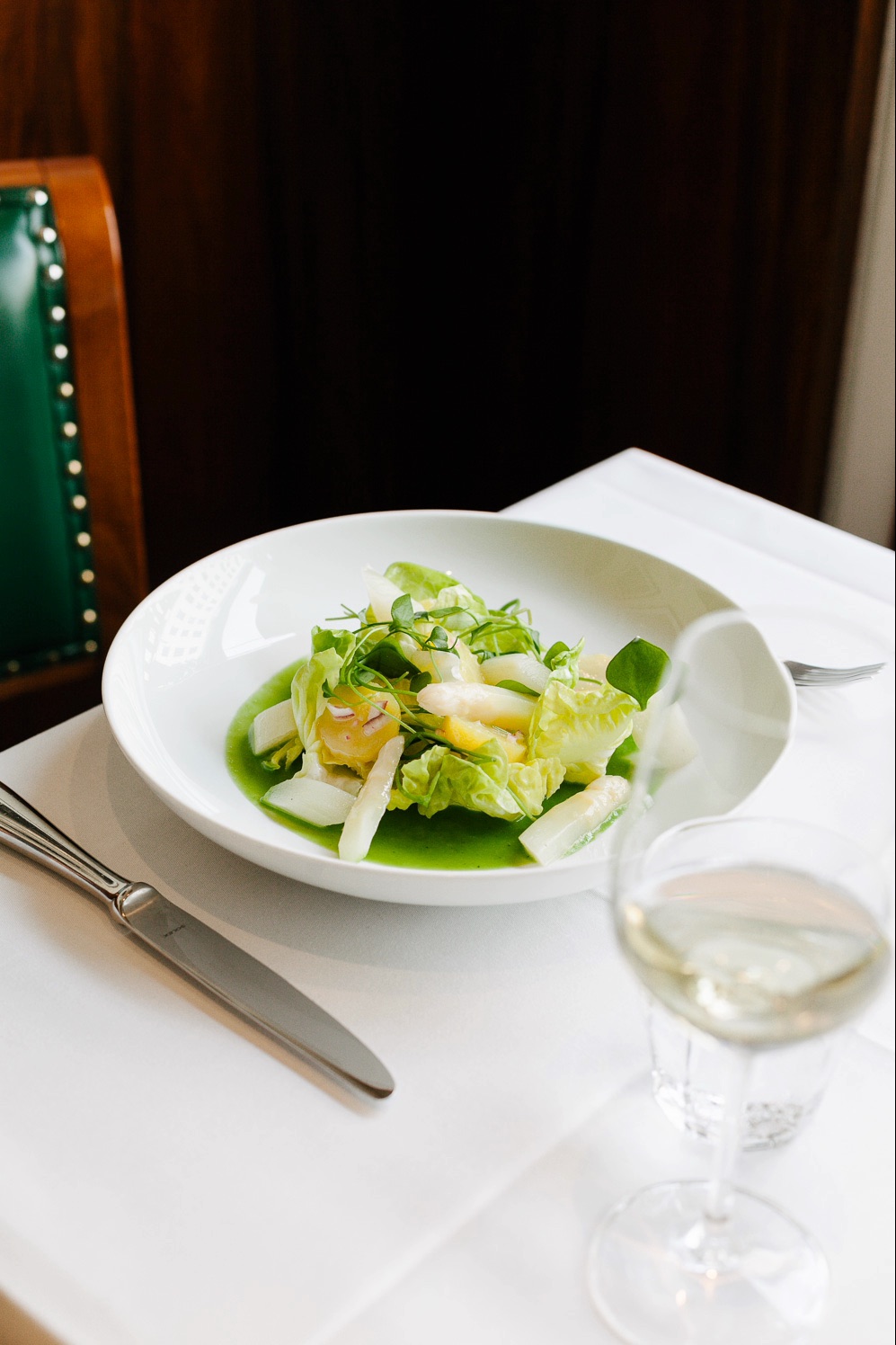 Salad in a white bowl with a glass of white wine at Einstein Unter den Linden