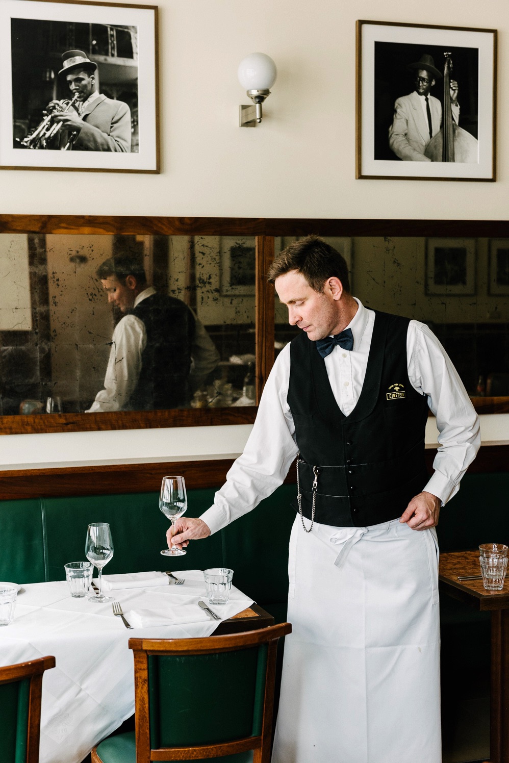 Waiter in a white apron setting a table at Einstein Unter den Linden