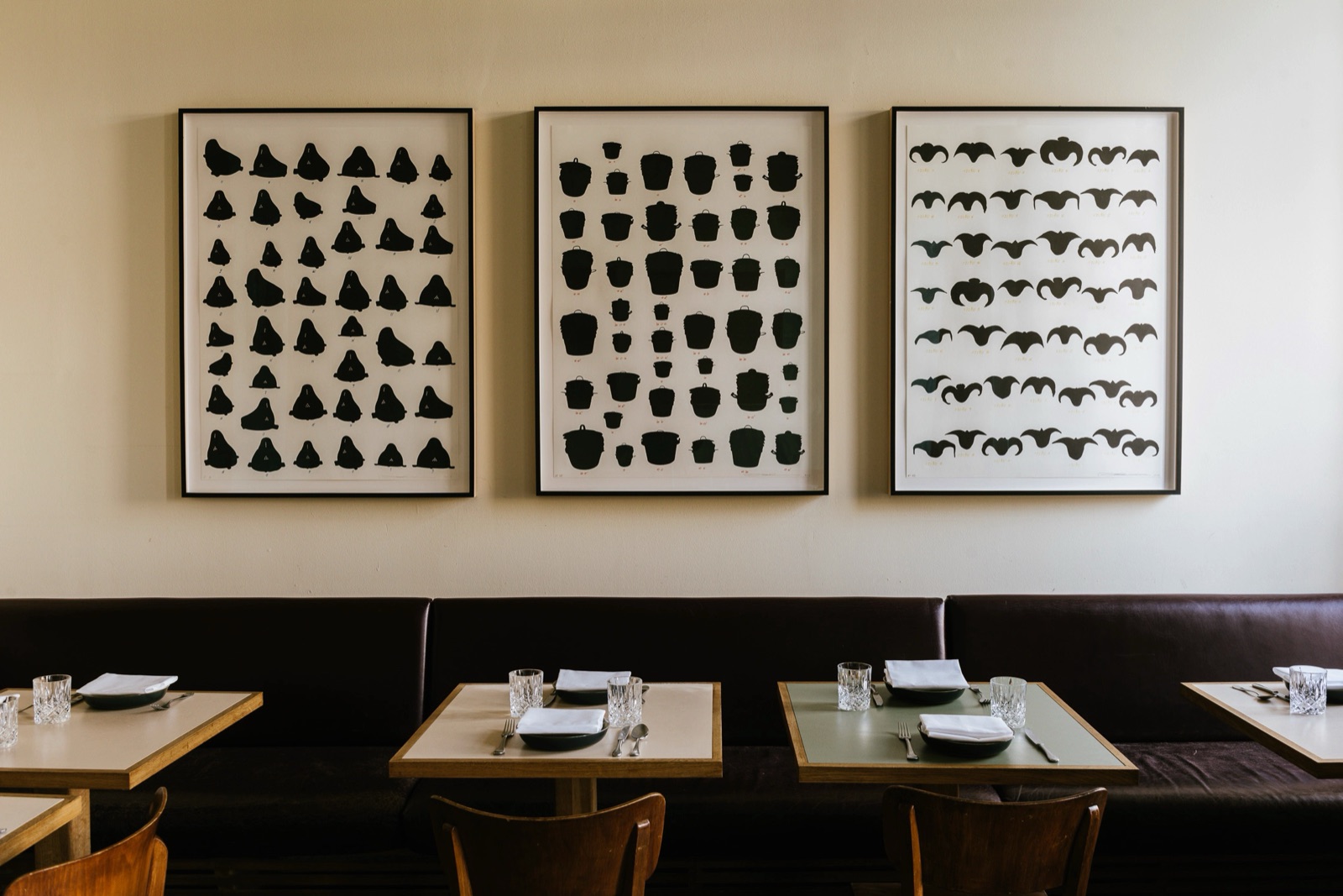 Kin Dee dining room with framed black and white wall art above set tables