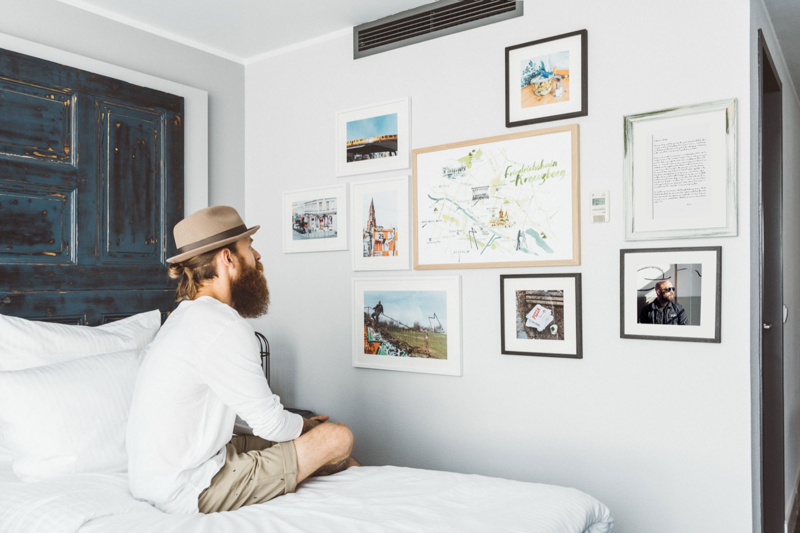 Guest on the bed in a Hotel Berlin, Berlin room with framed You, Me & Berlin stories on the wall