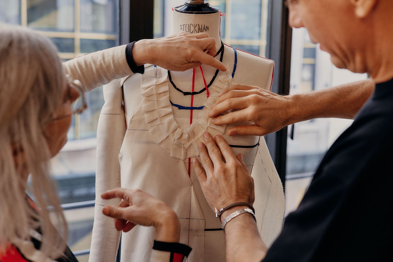 Atelier team fitting a pleated garment on a dress form