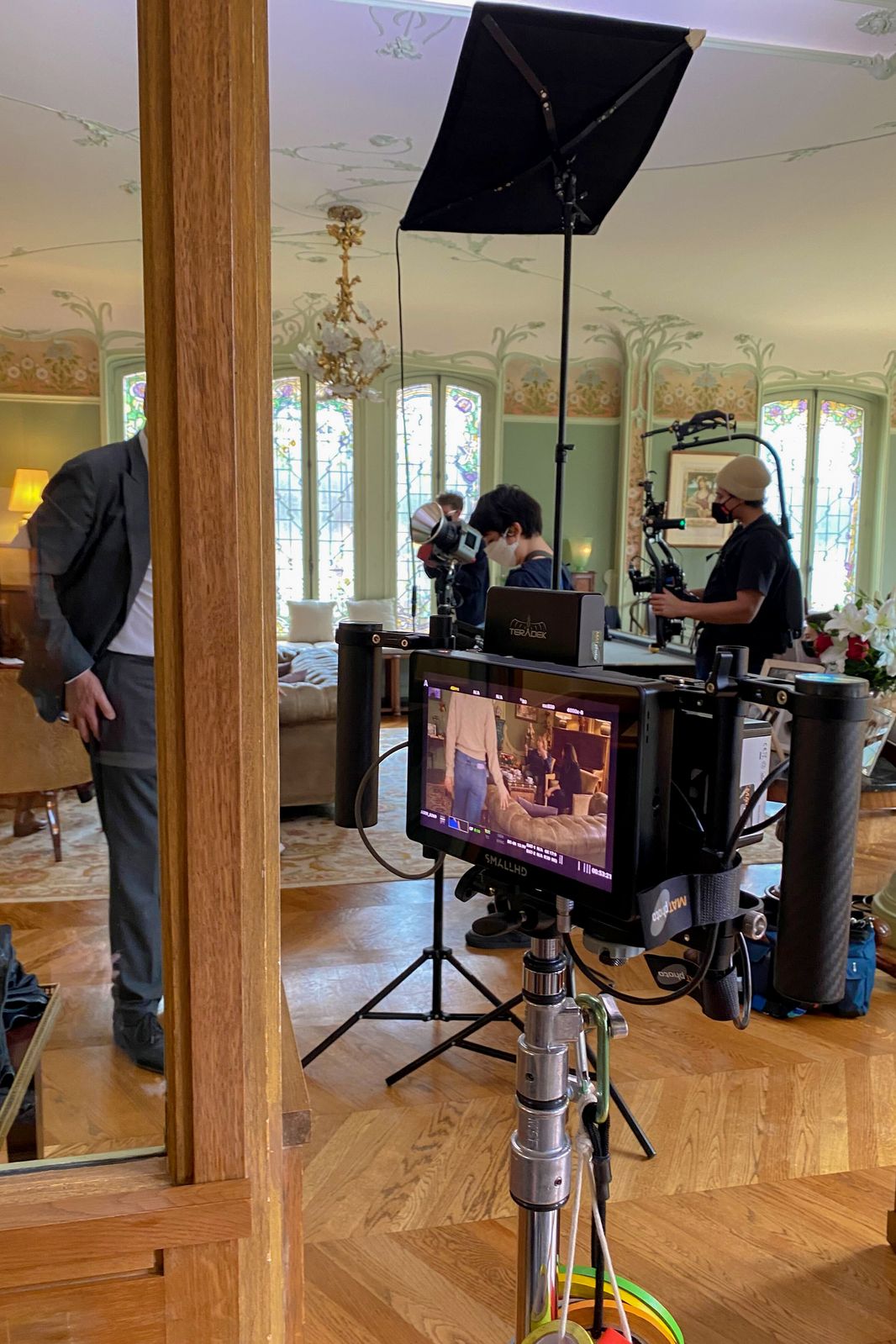 Behind the scenes: camera monitor and lights on set in a wood-panelled room