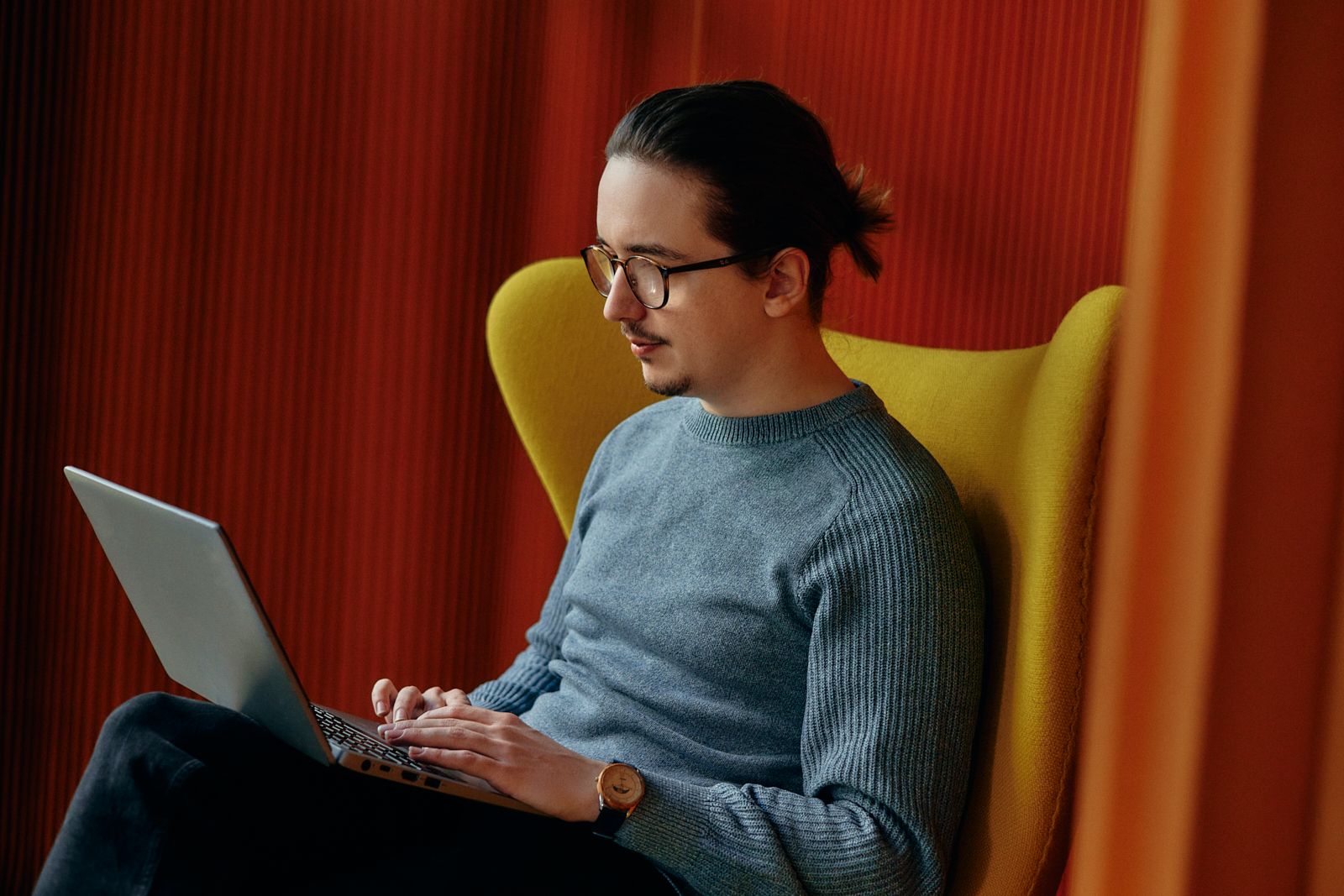 Finance employee working on a laptop in a yellow armchair