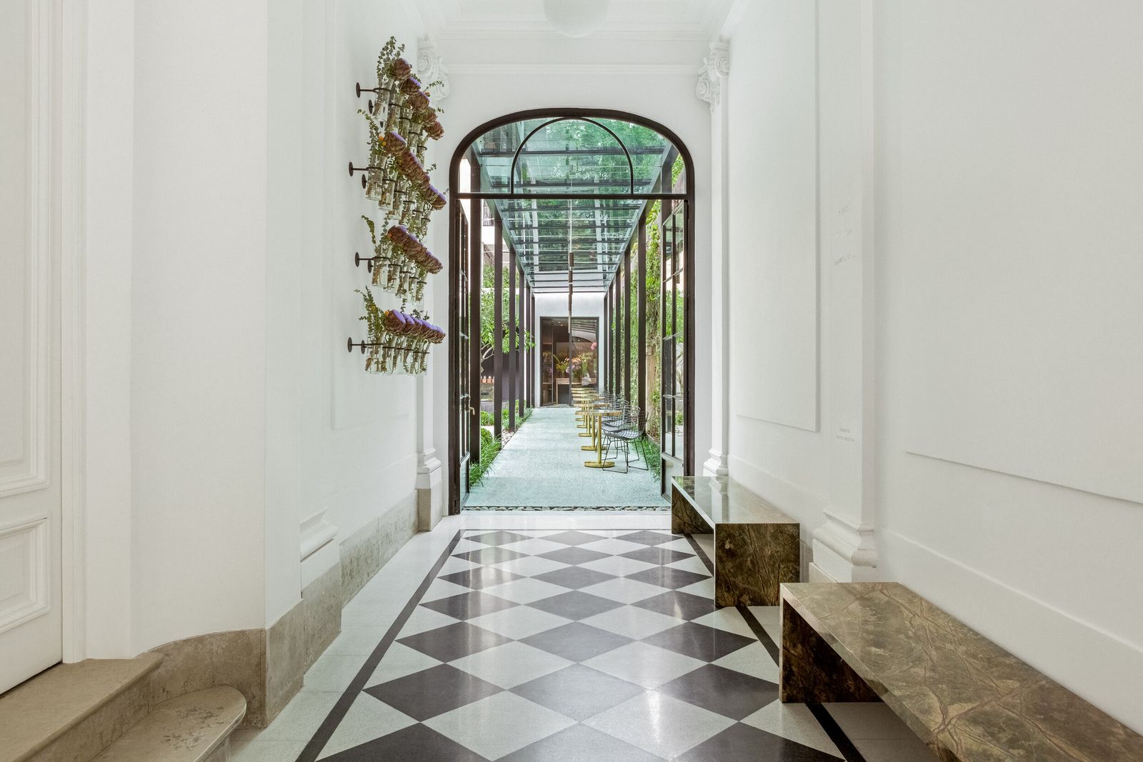White hallway with a checkered marble floor leading to a glass conservatory at Casa Cavia