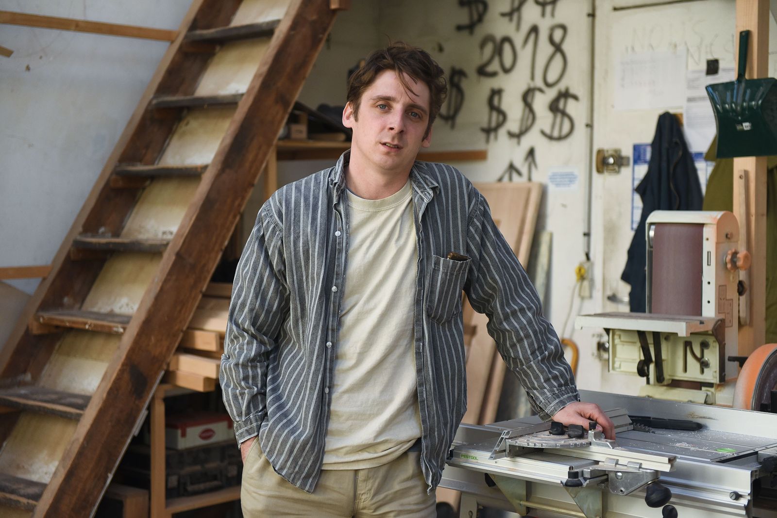 Artist Camille Blatrix standing among workbenches in his Paris studio