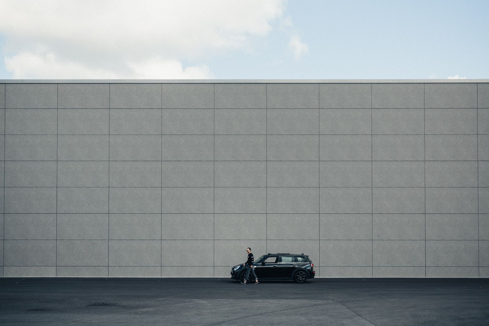 A black MINI parked in front of a long grey facade in Berlin, from the portrait of photographer Noshe