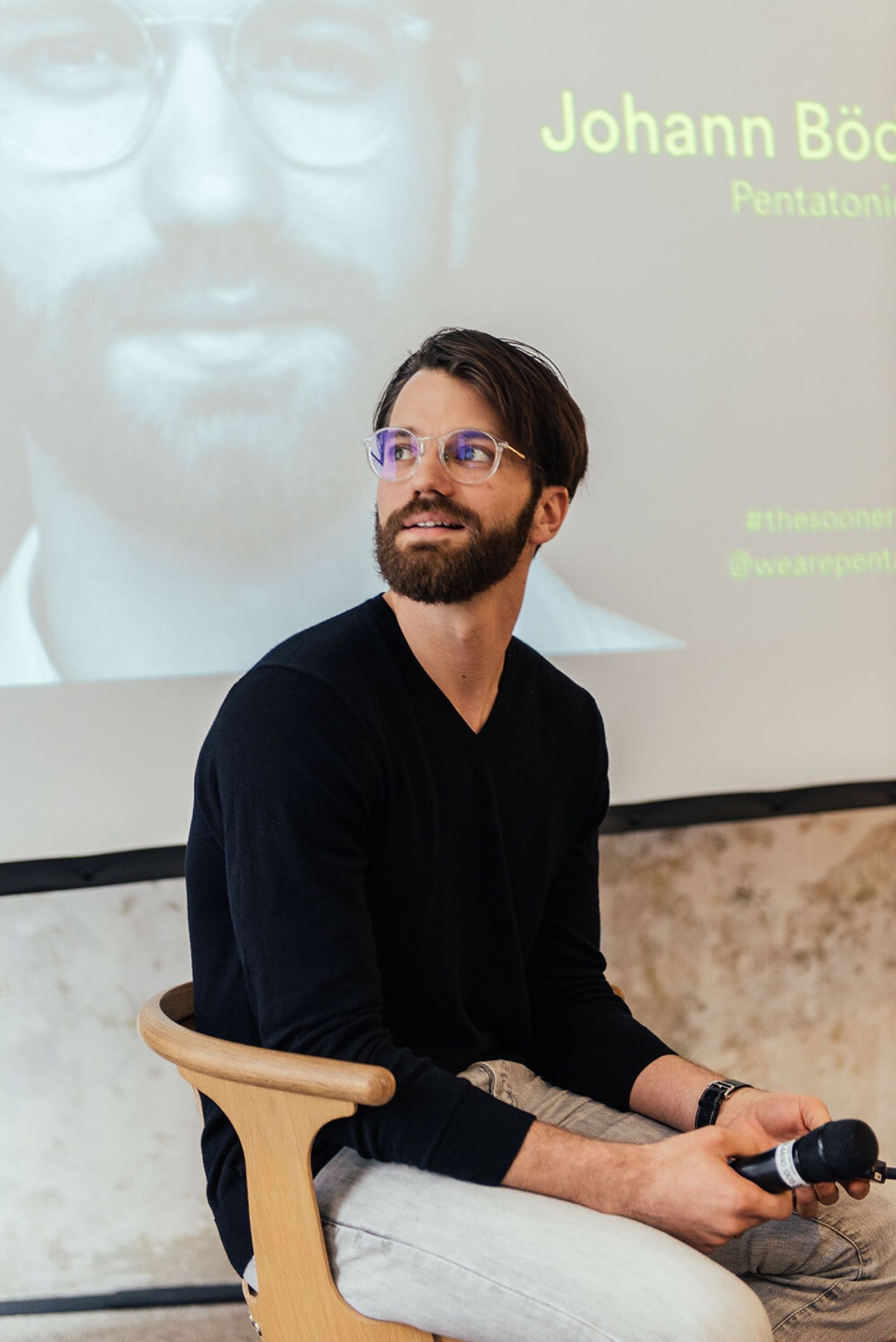 Speaker on stage in front of a projected portrait, The Sooner Now Berlin 2019