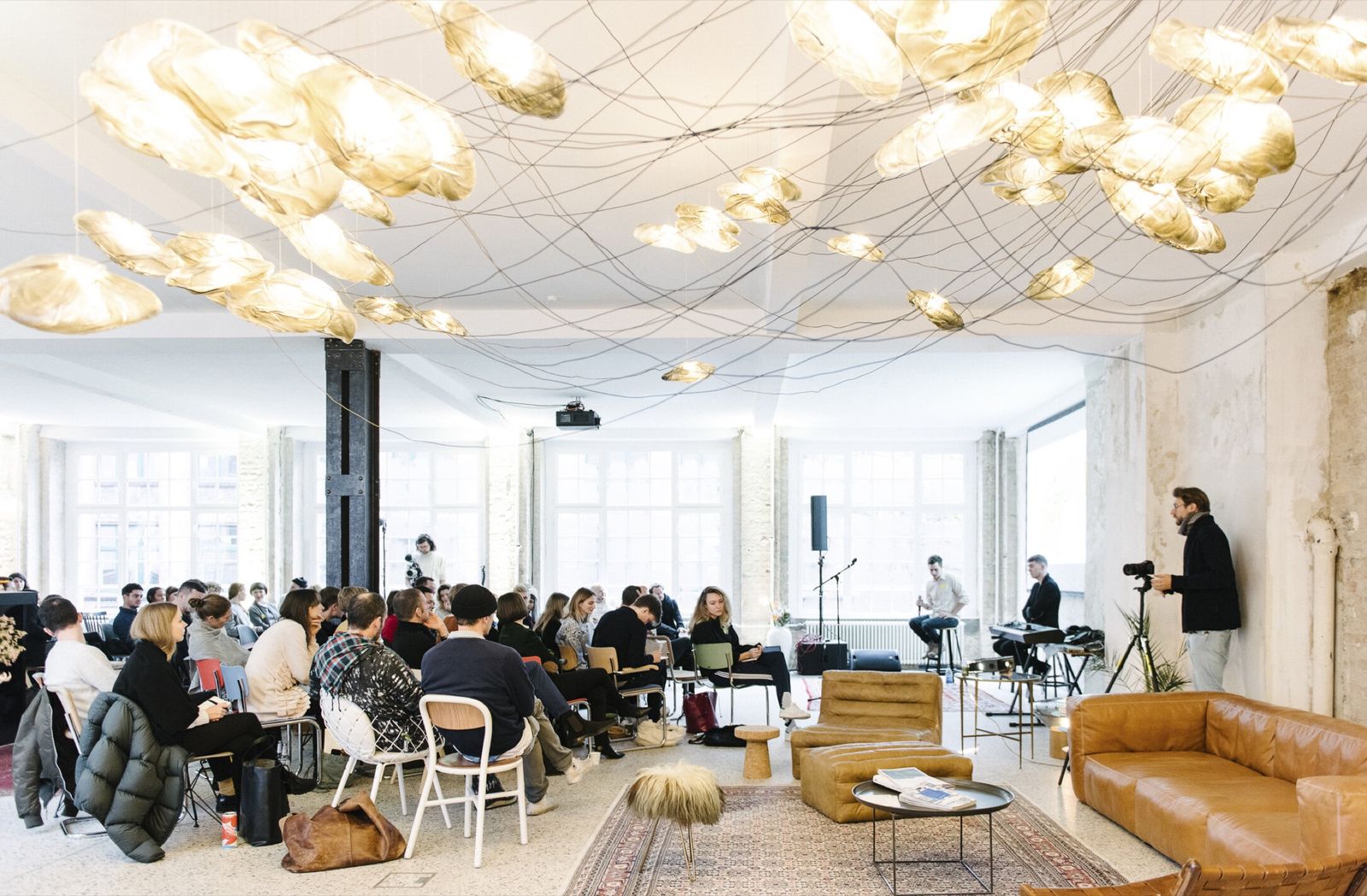 Audience at a talk under a hanging light installation at FvF Friends Space Berlin