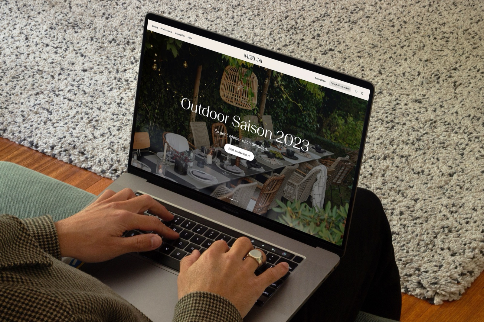 Hands typing on a laptop showing the Mizzuni website Outdoor Season 2023 page
