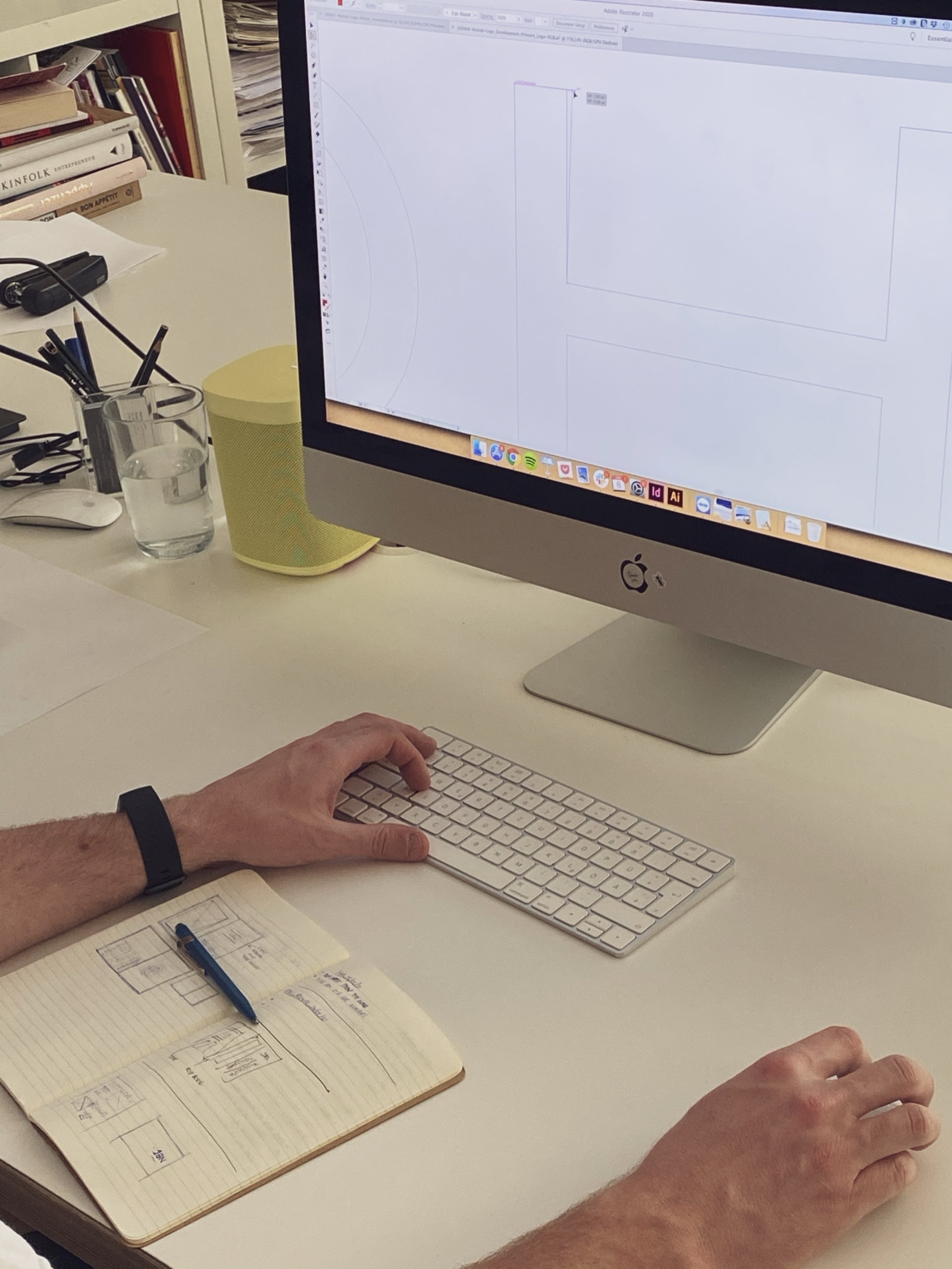 Designer sketching MOHAB logo ideas in a notebook at a desk