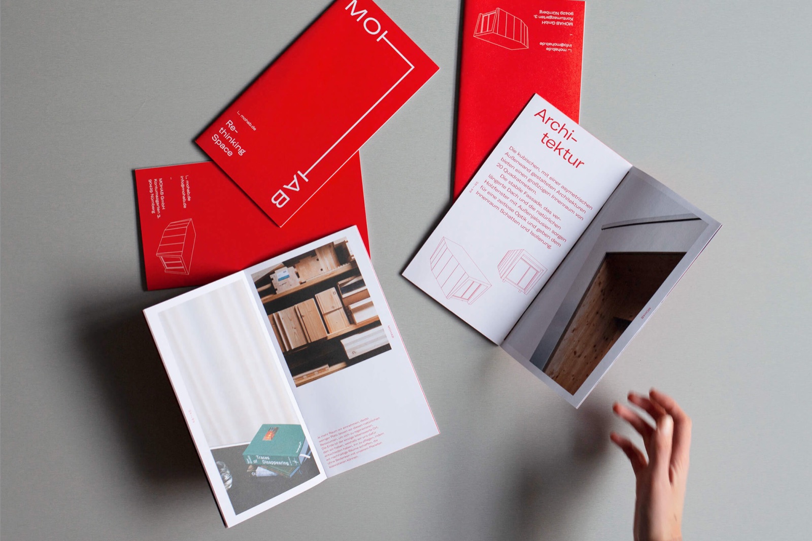 MOHAB press kit booklets with red covers spread on a grey surface