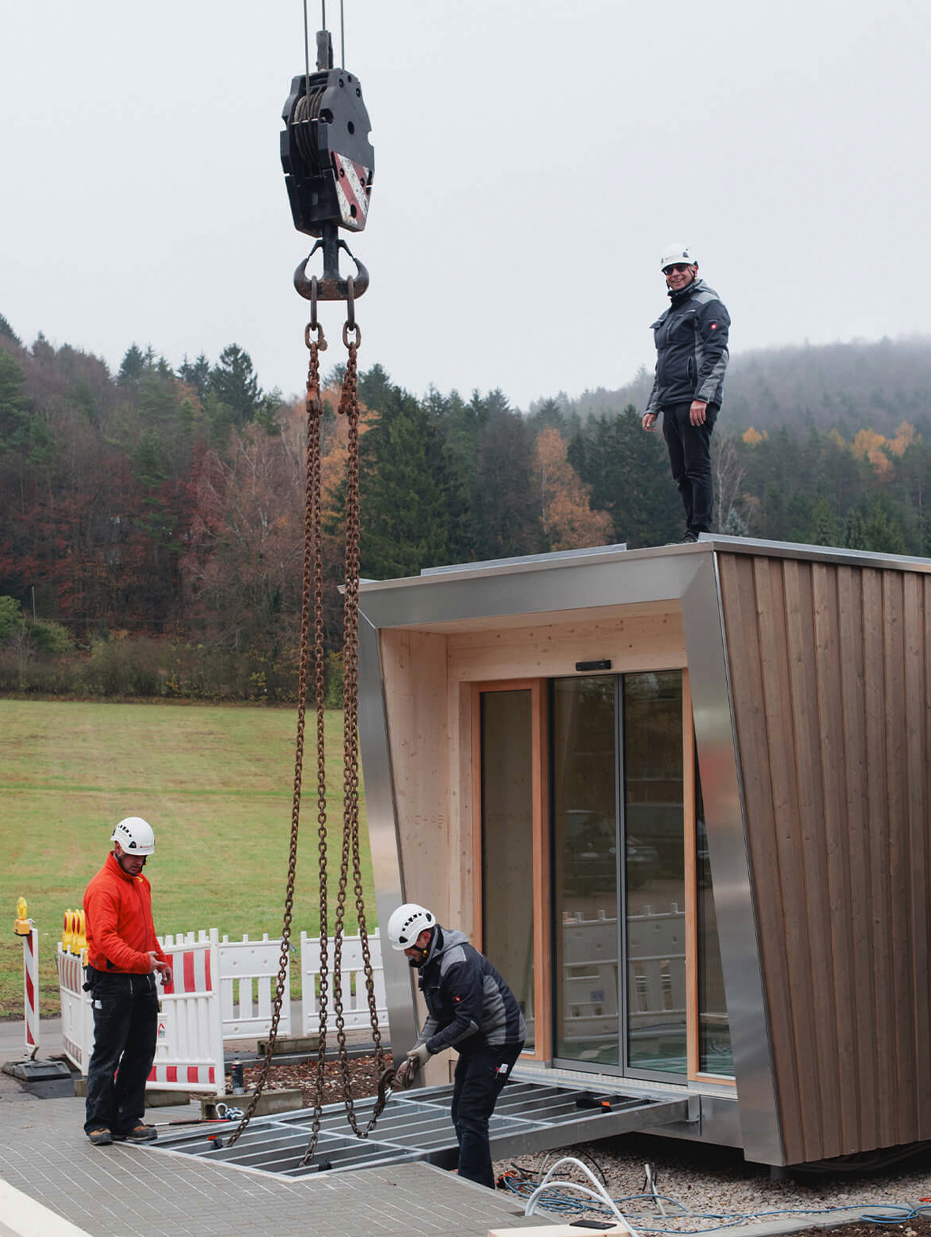 Crane lowering a MOHAB Space unit into place with workers on site