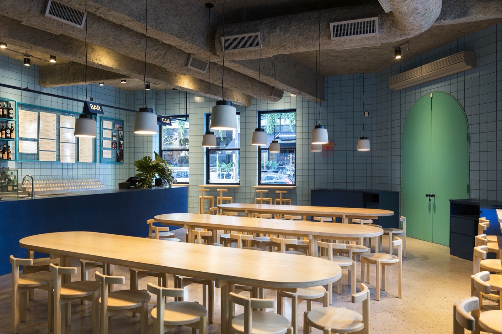 ORNO dining room with long shared wooden tables and blue tiles