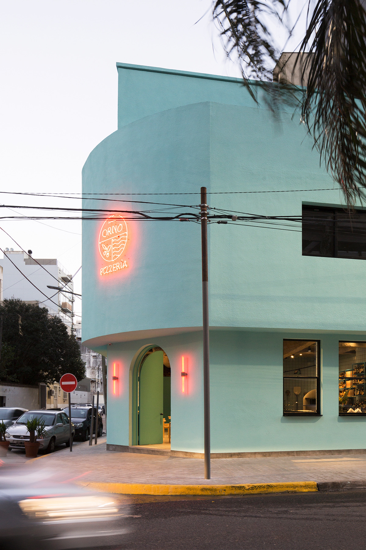 ORNO pizzeria exterior, mint corner building with neon logo at dusk