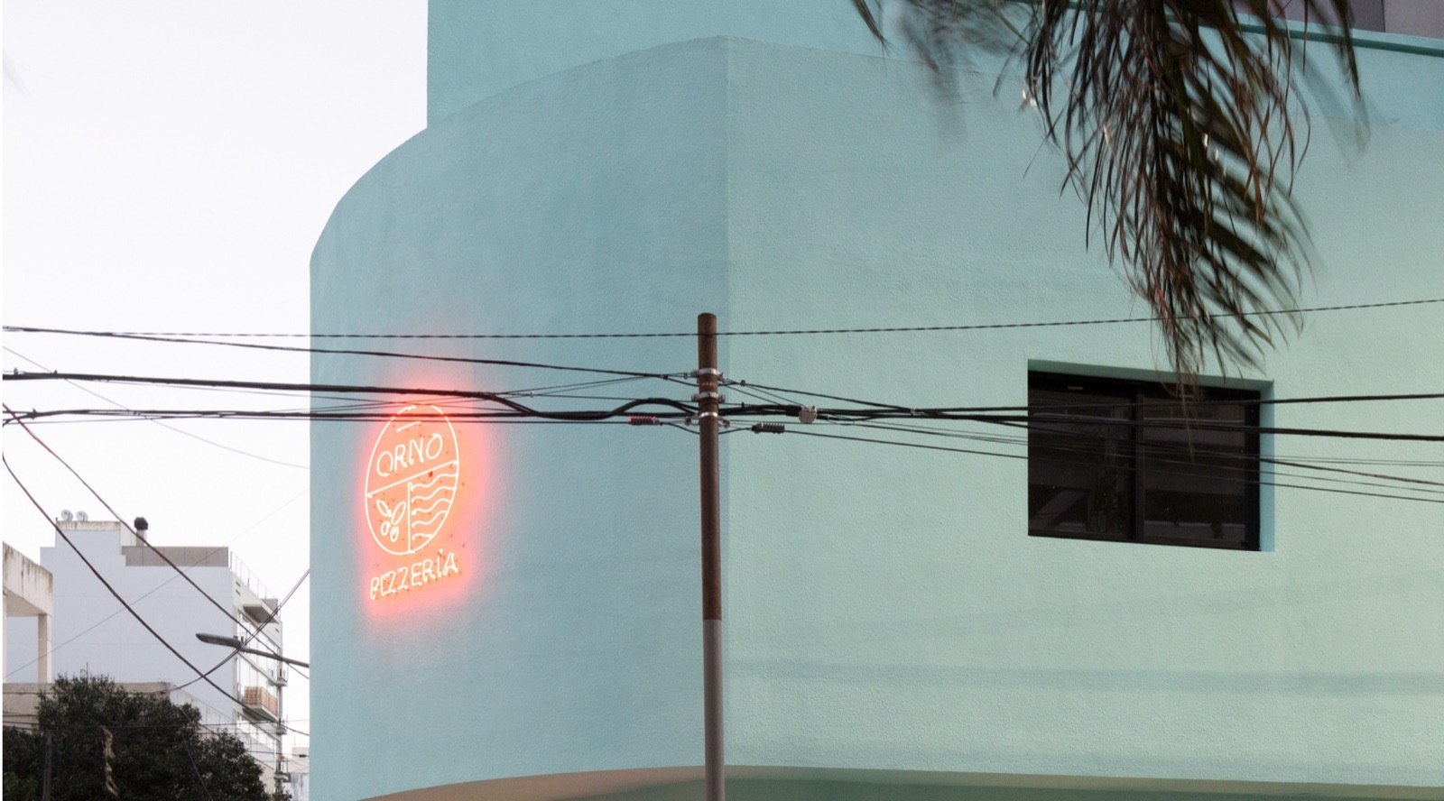 ORNO pizzeria exterior with the red neon logo sign on a mint corner building in Buenos Aires