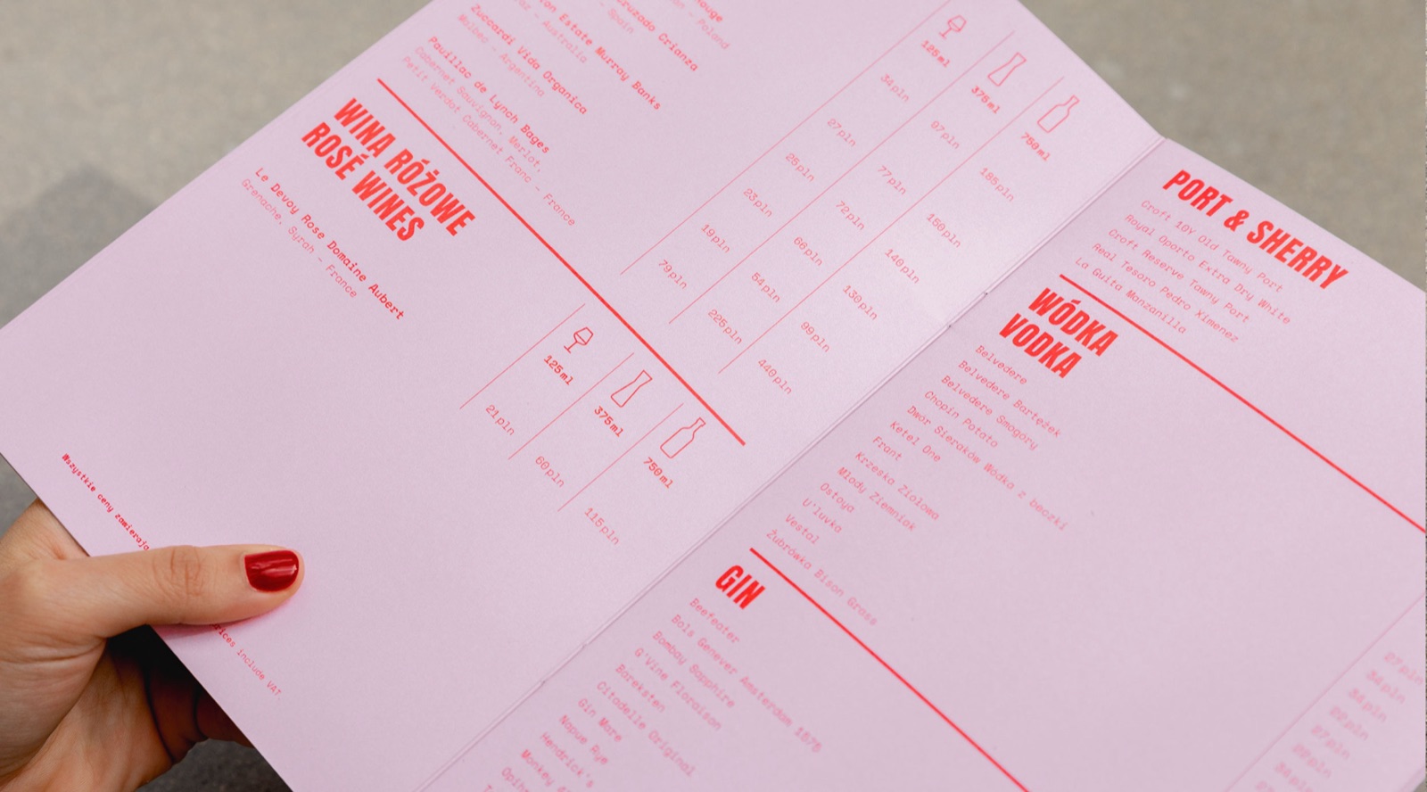 Hand holding the open Loreta drinks menu with red typography on pink
