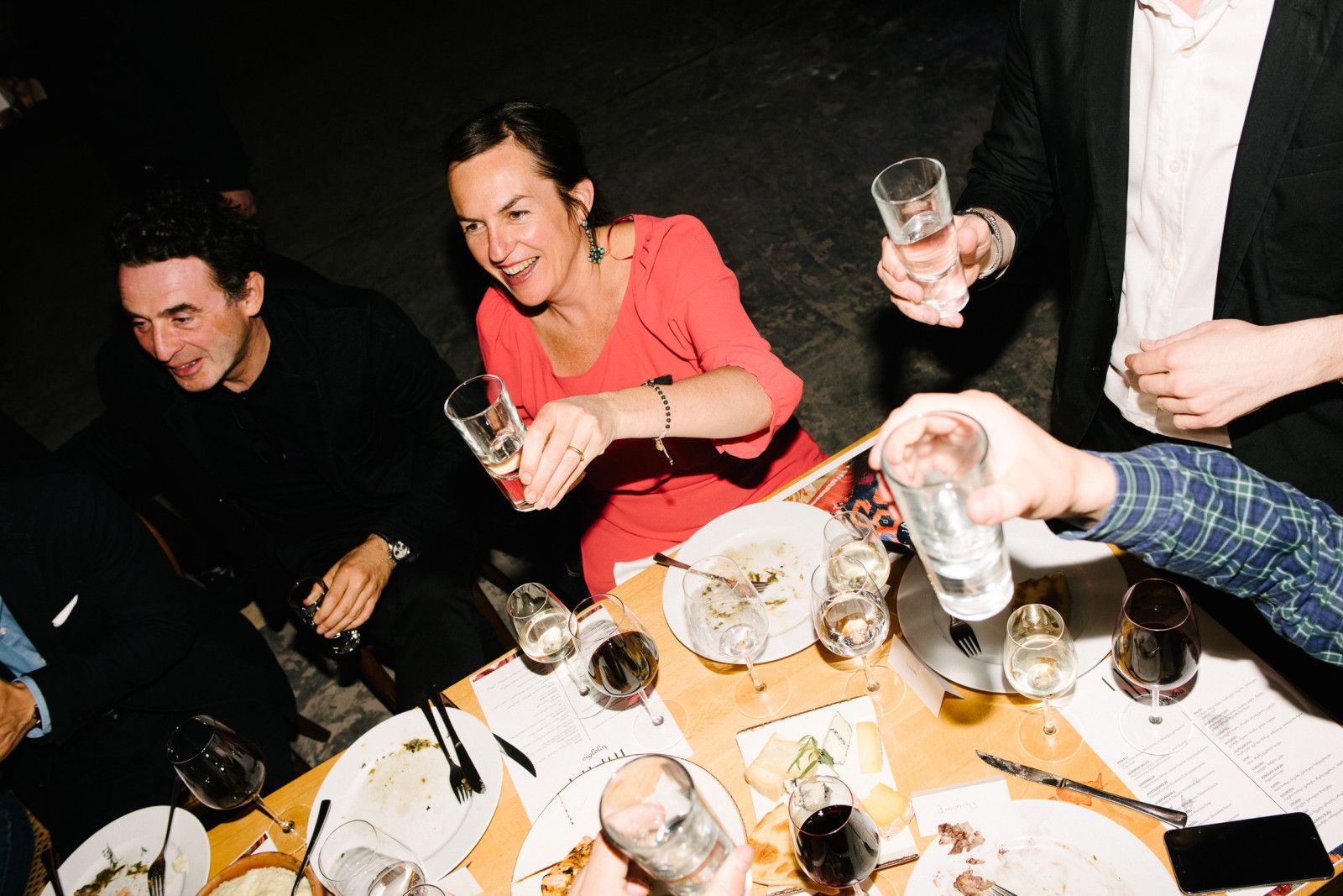 Guests laughing and raising small glasses at the Supra dinner