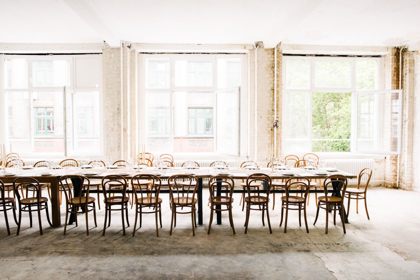 Long dinner table set for the Supra in a white loft