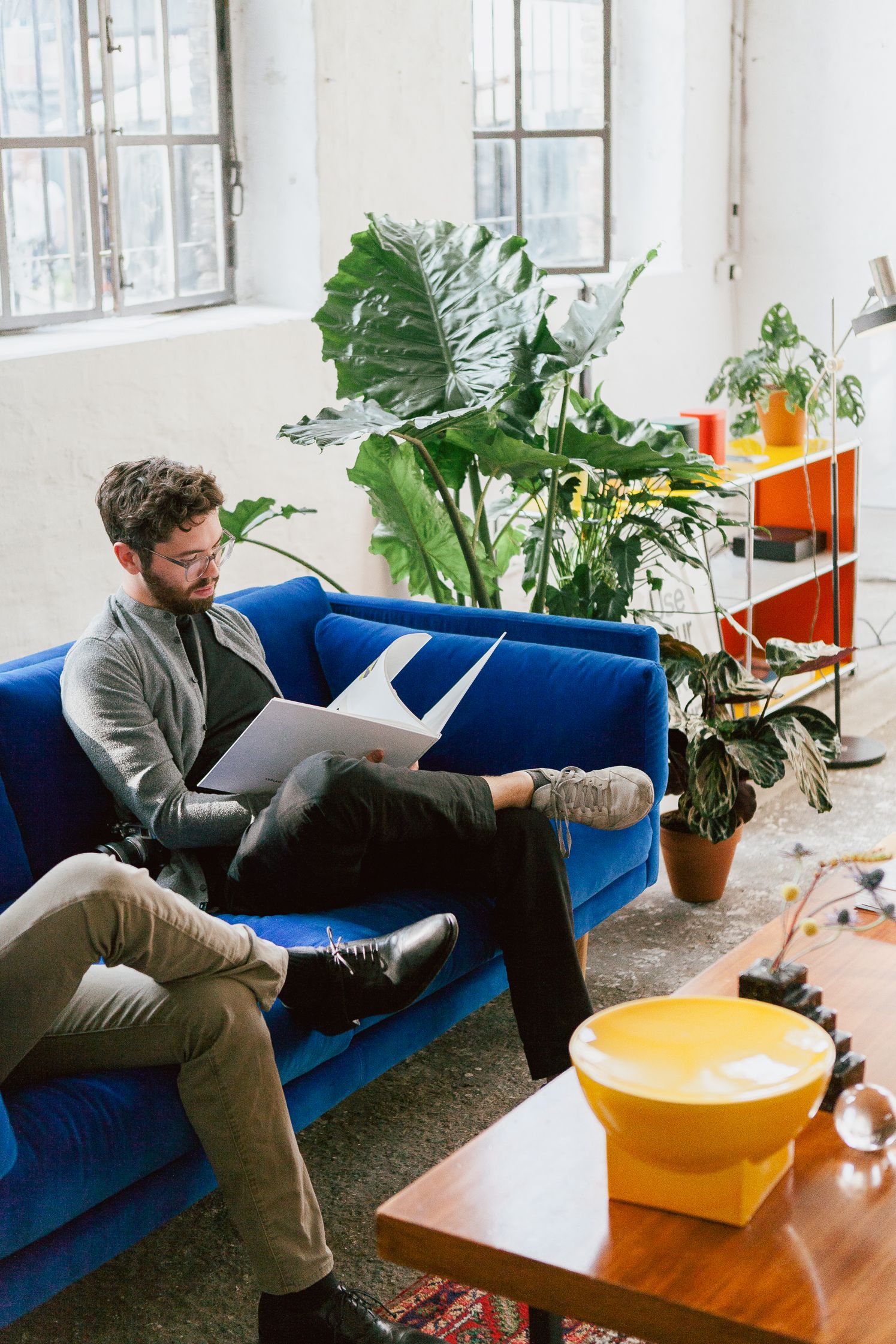 Guest reading on a blue velvet sofa in the Sonos IFA hub