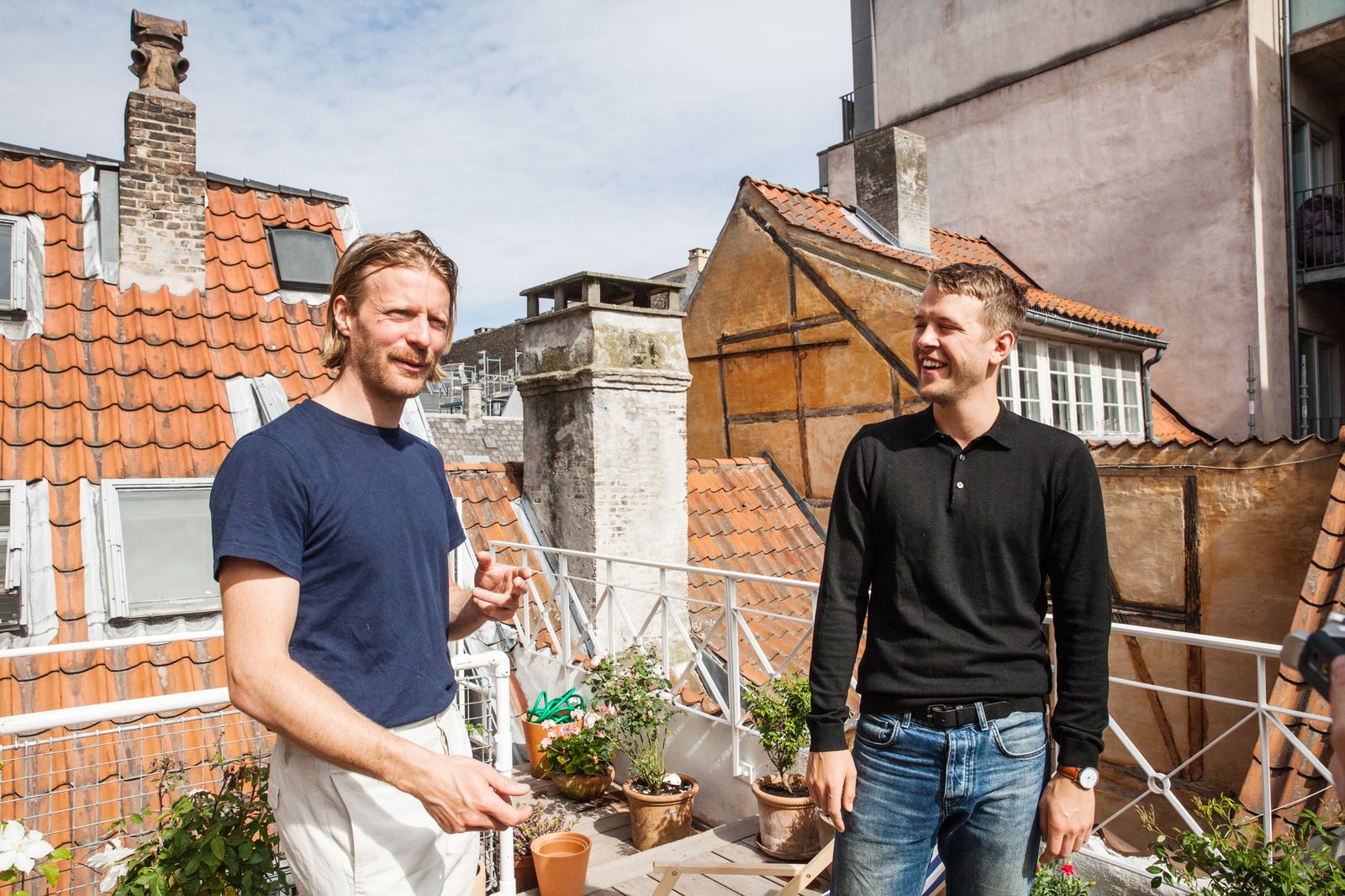 Two designers talking on a rooftop terrace above a Copenhagen street